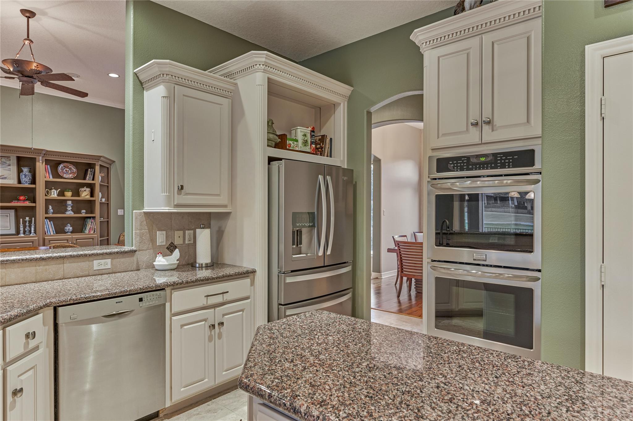 Kitchen with white cabinets, granite counters, stainless appliances, and a large island.