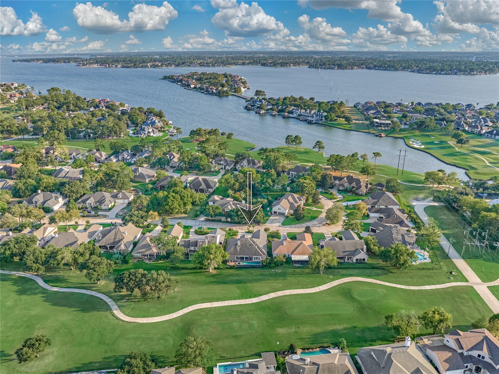 Aerial view of the home marked by an arrow, beside a golf course and lake.