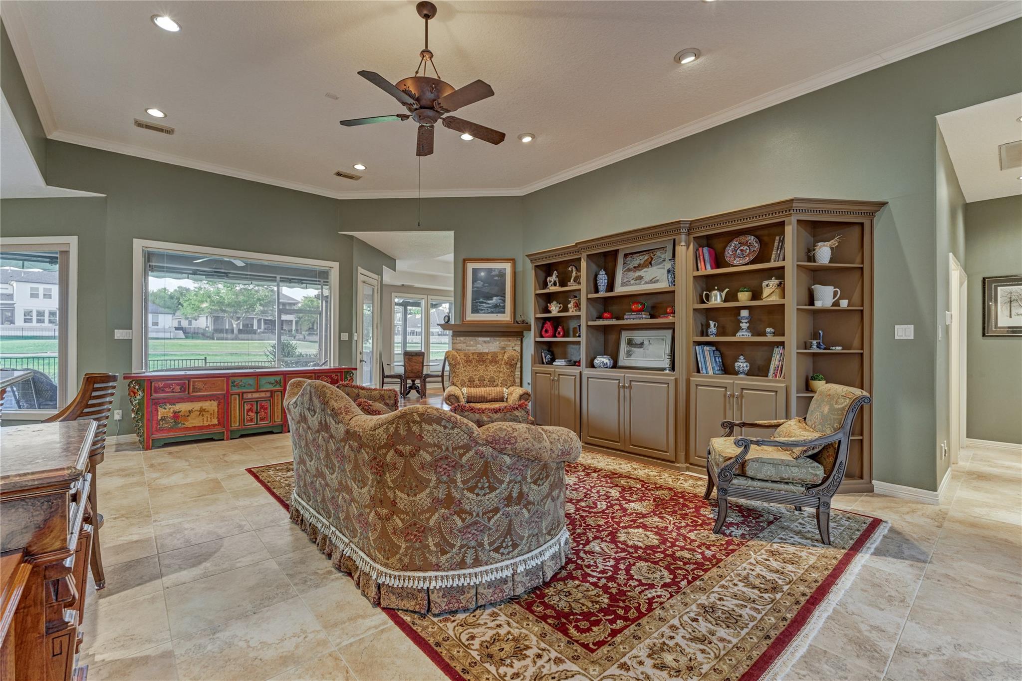 Living room with built-in wooden shelves, patterned seating, and layered red and cream rugs.
