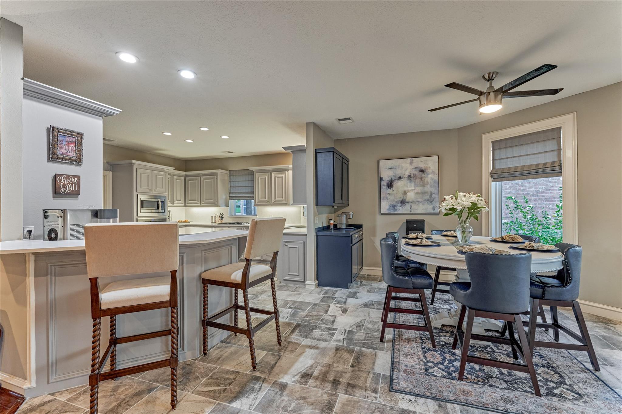 Open kitchen and dining area with a white island, bar stools, and a set table by the window.