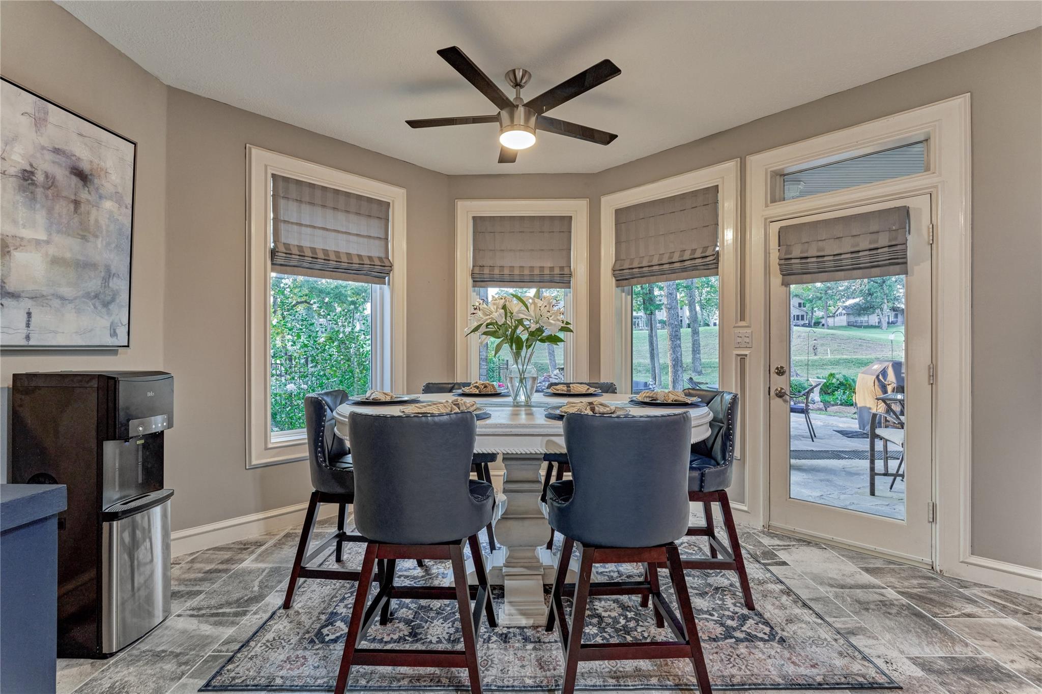 Dining room with a set table, large windows, and a glass door to the patio.