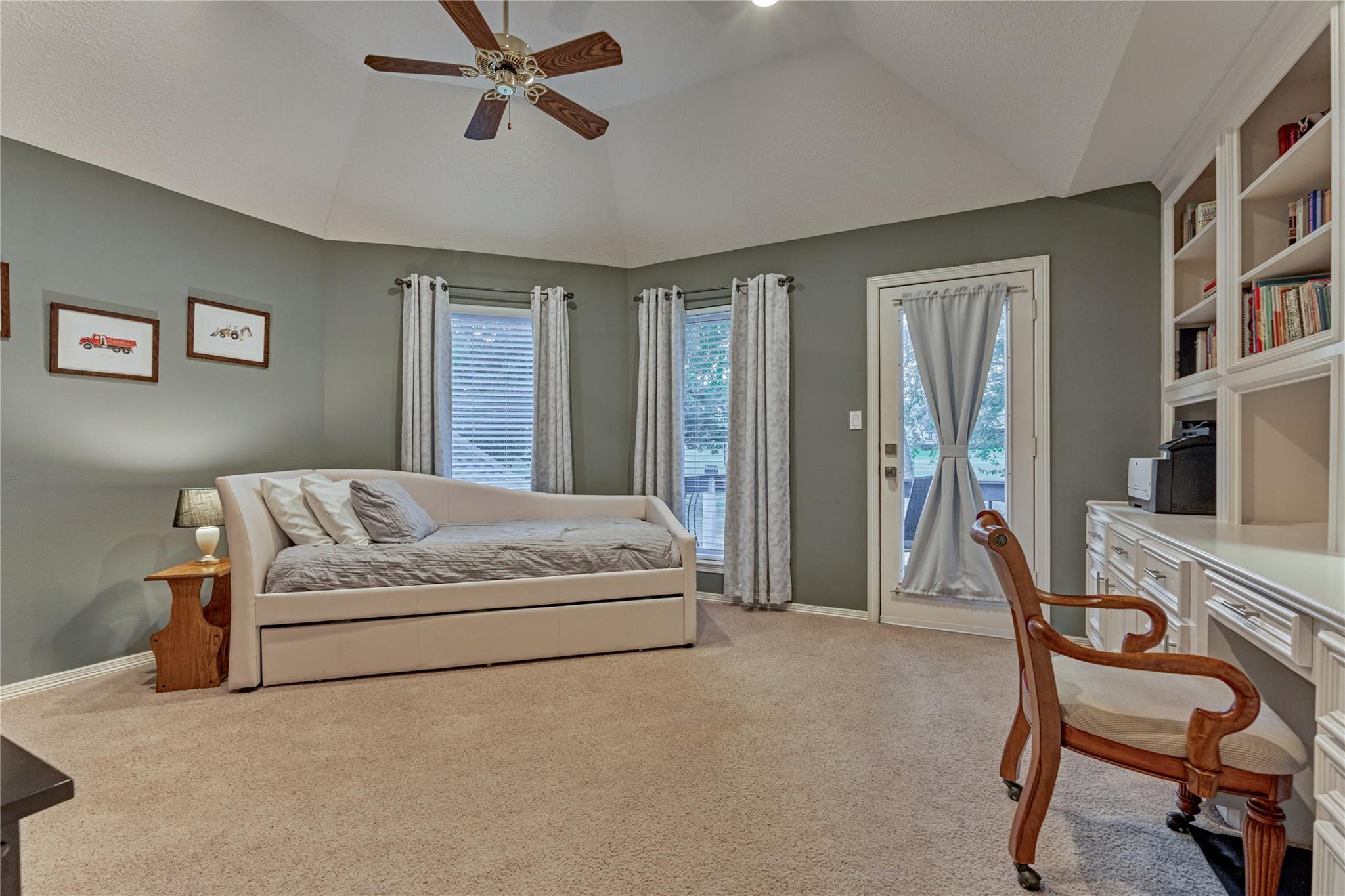 Bedroom with a cream daybed, curtained windows, and built-in white bookcases.