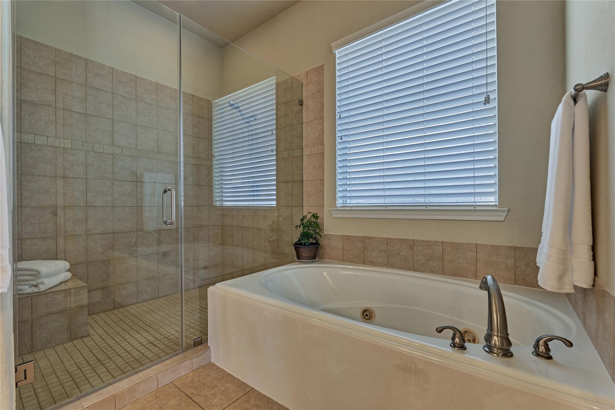 Bathroom with a large soaking tub beside a glass-enclosed tiled shower.