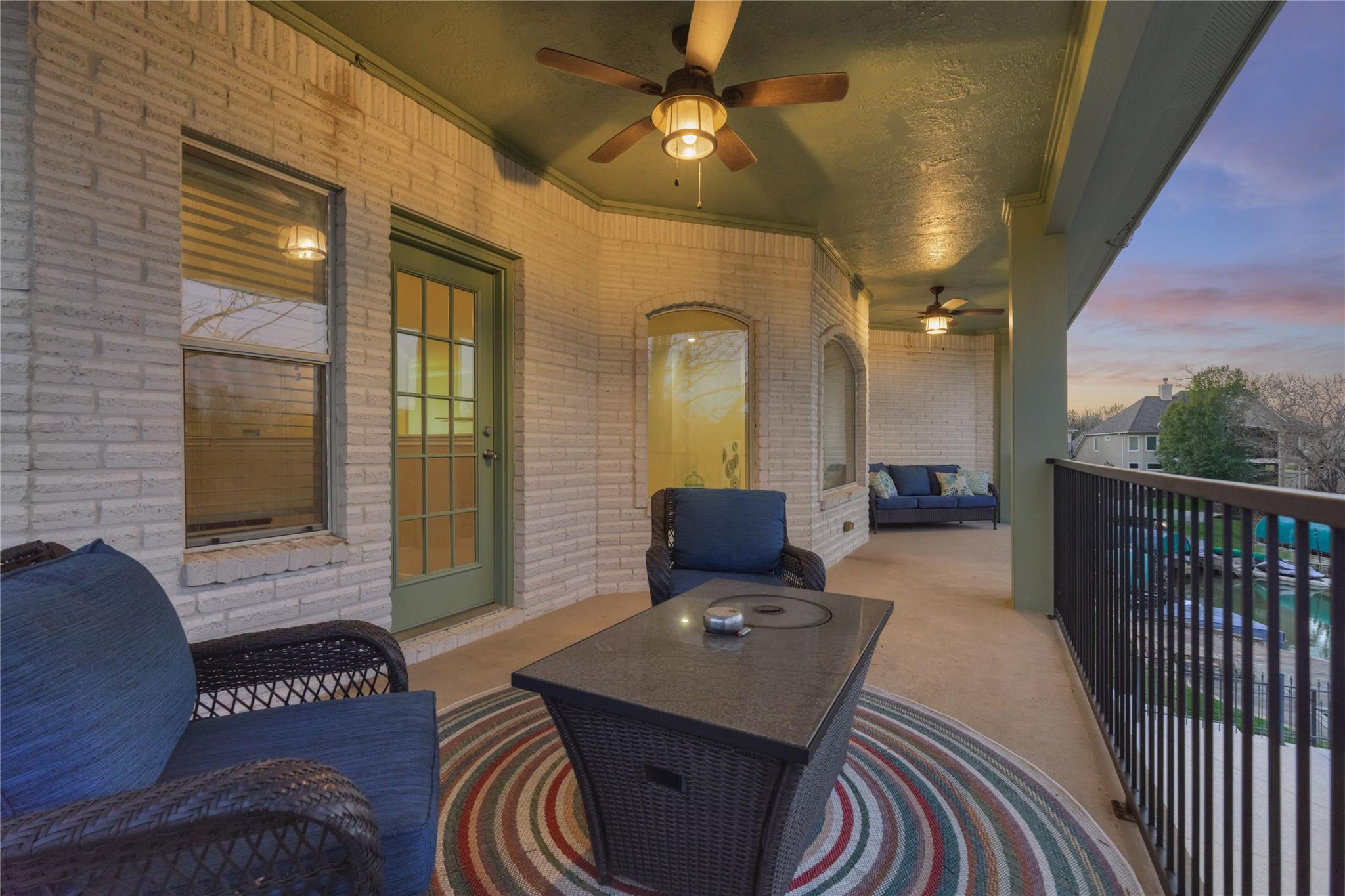 Covered brick porch with blue seating, ceiling fans, and a view toward the pool.