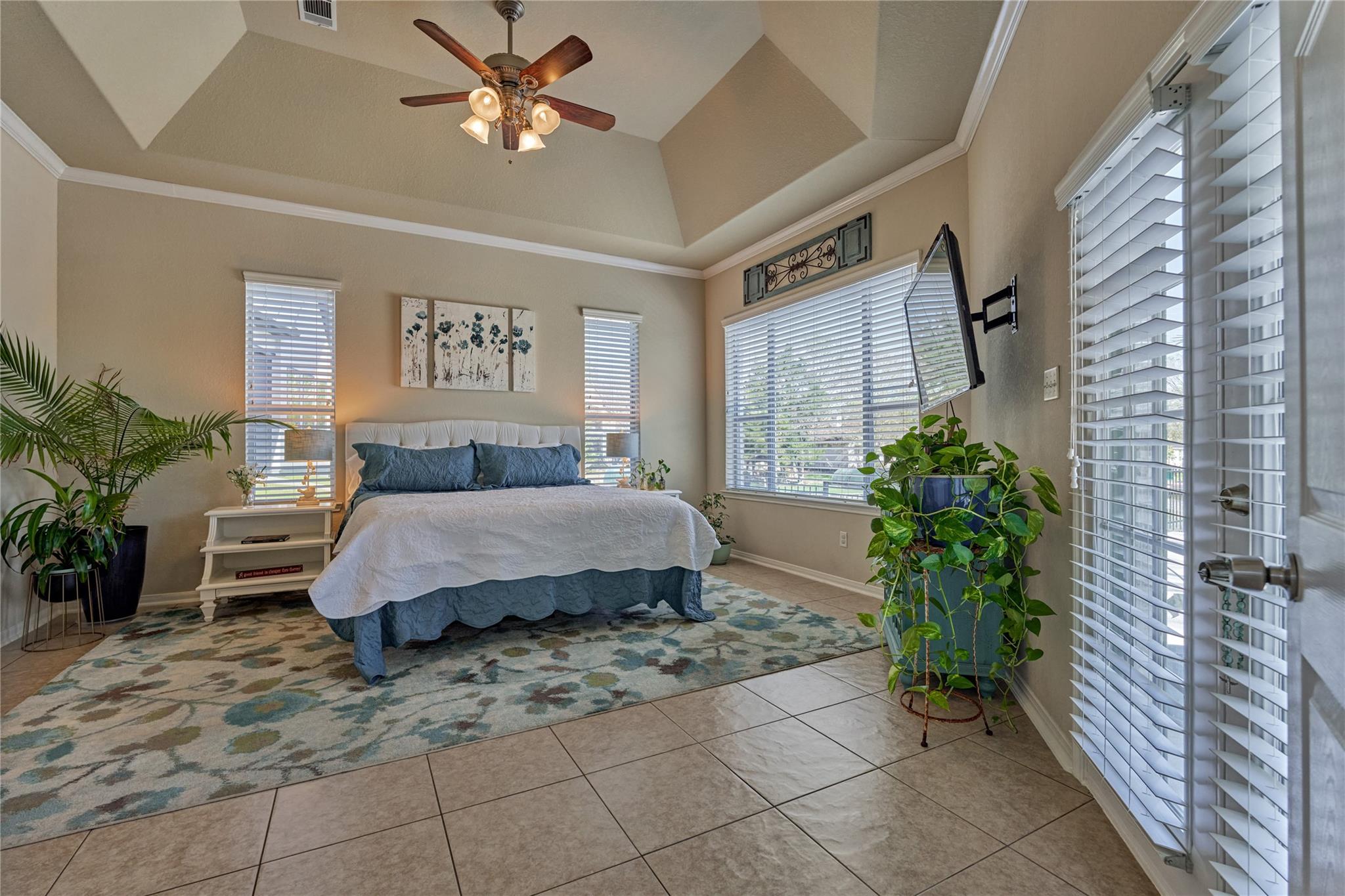 Bedroom with a blue-and-white bed, patterned rug, large windows, and vaulted ceiling.
