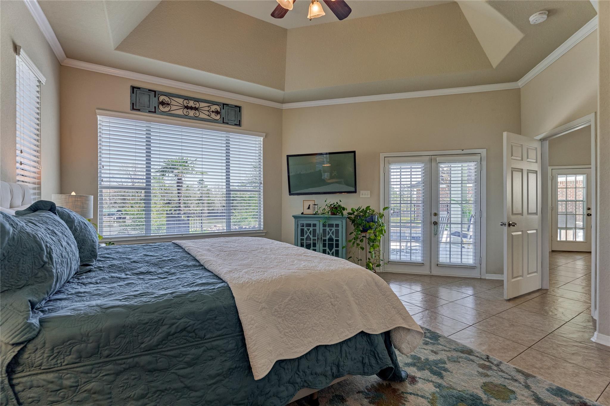 Furnished bedroom with a vaulted ceiling, blue-and-white bed, and glass patio doors.