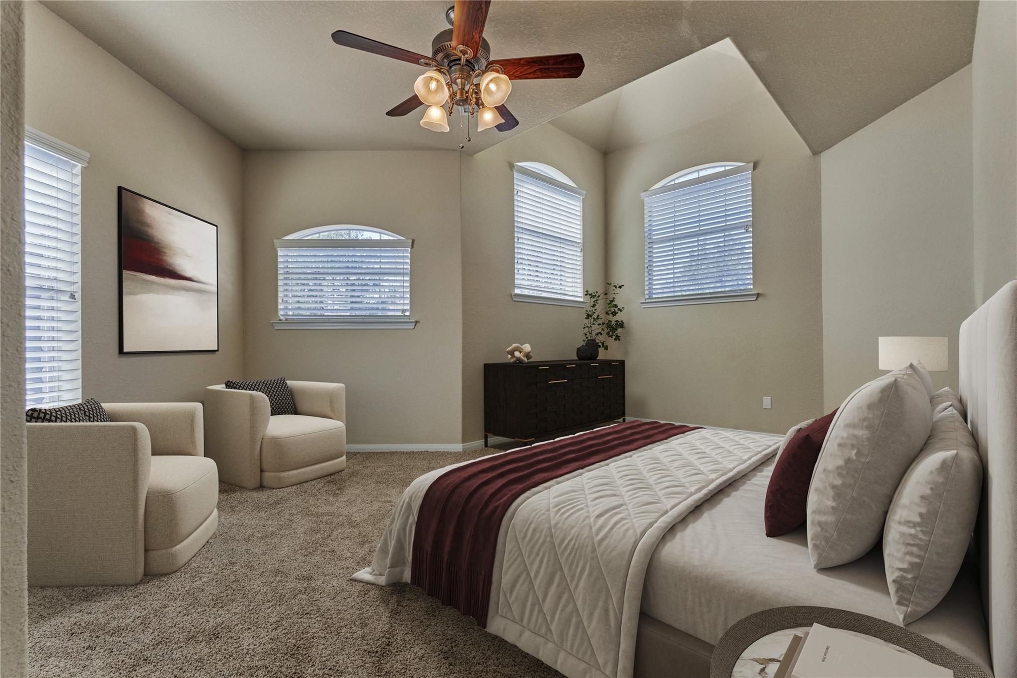 Furnished bedroom with a king bed, vaulted ceiling, arched windows, and two armchairs.