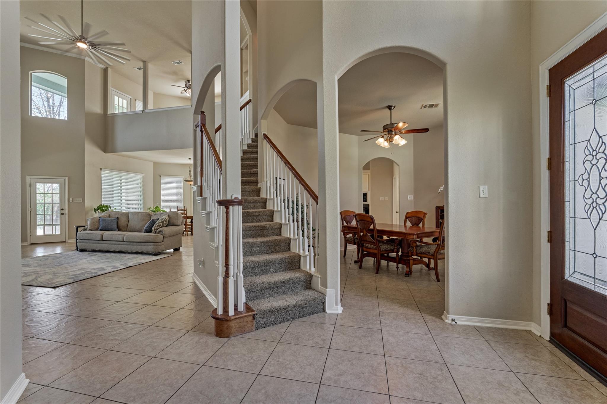 Two-story entry foyer with a carpeted staircase, tiled floors, and adjoining living and dining rooms.