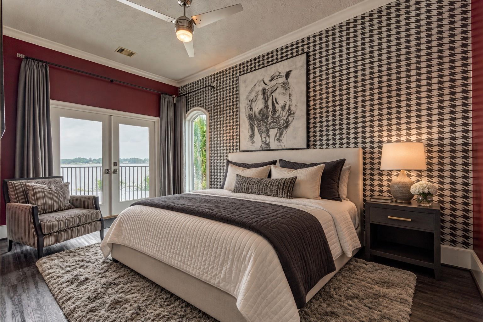 Bedroom with houndstooth wallpaper, a large bed, and balcony doors overlooking water.