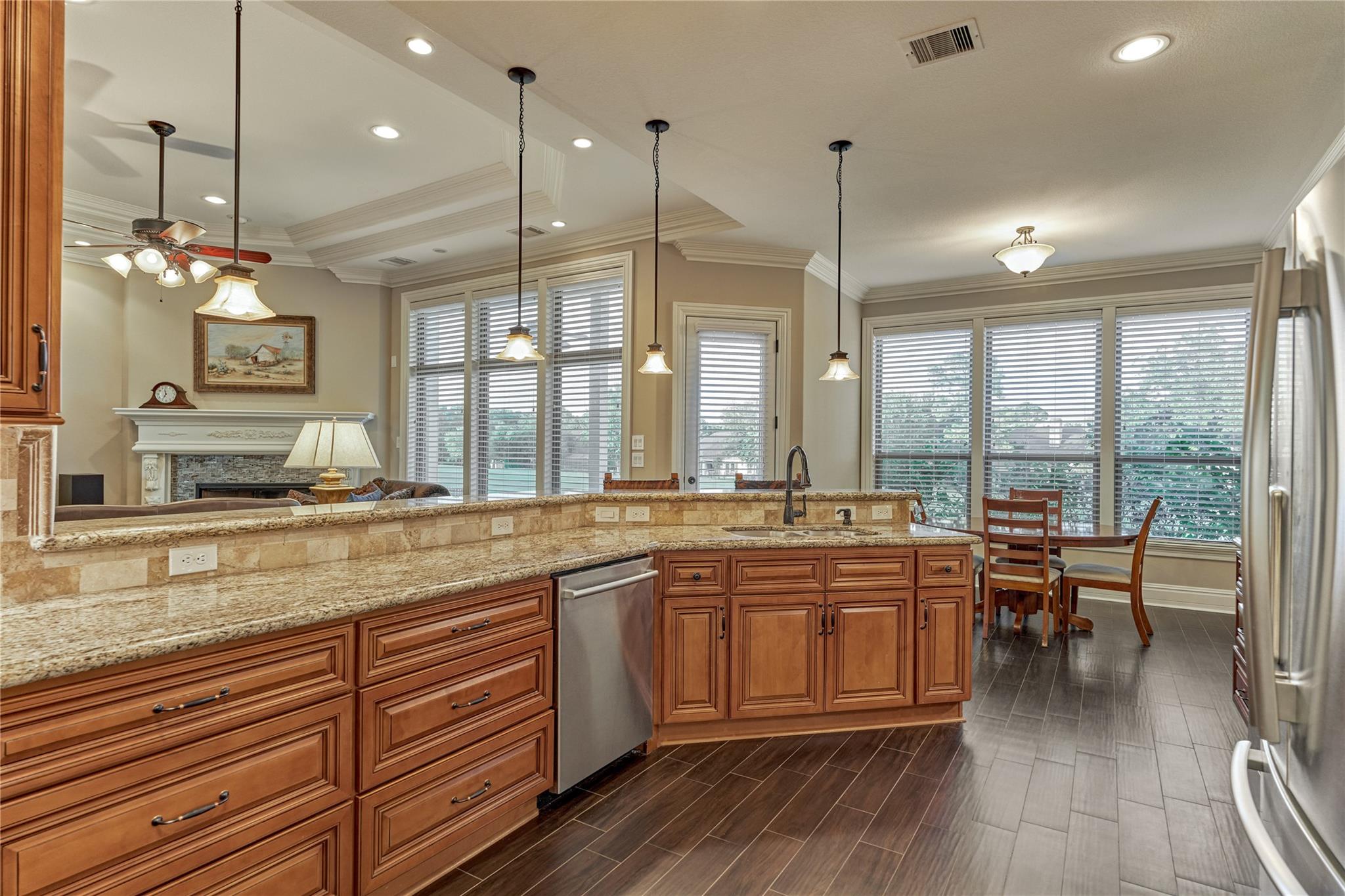 Kitchen with wood cabinetry and granite island, opening to a breakfast nook and living room.