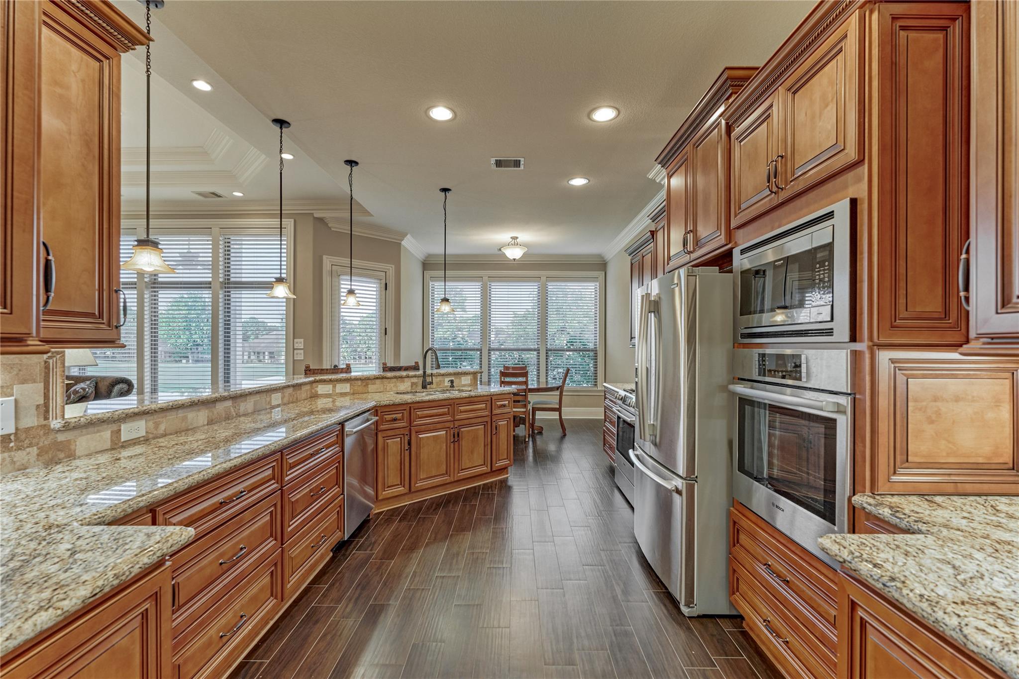 Kitchen with wood cabinets, granite counters, stainless steel appliances, and large windows.