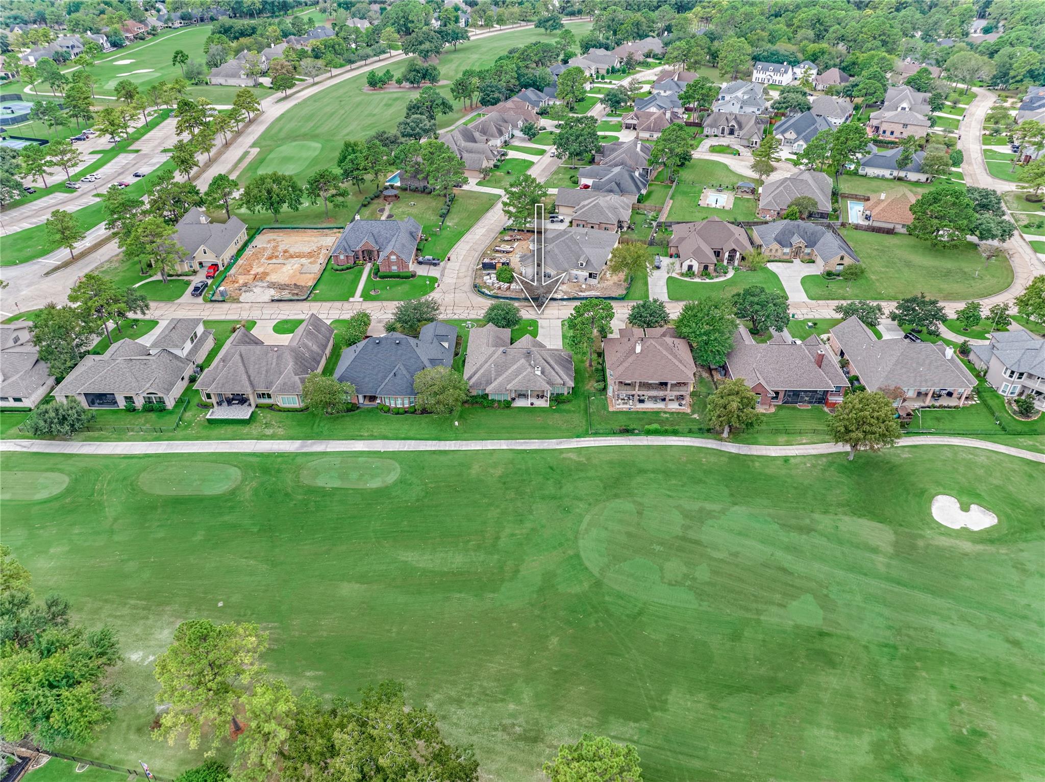 Aerial view of the property beside a golf course, marked by a white arrow.