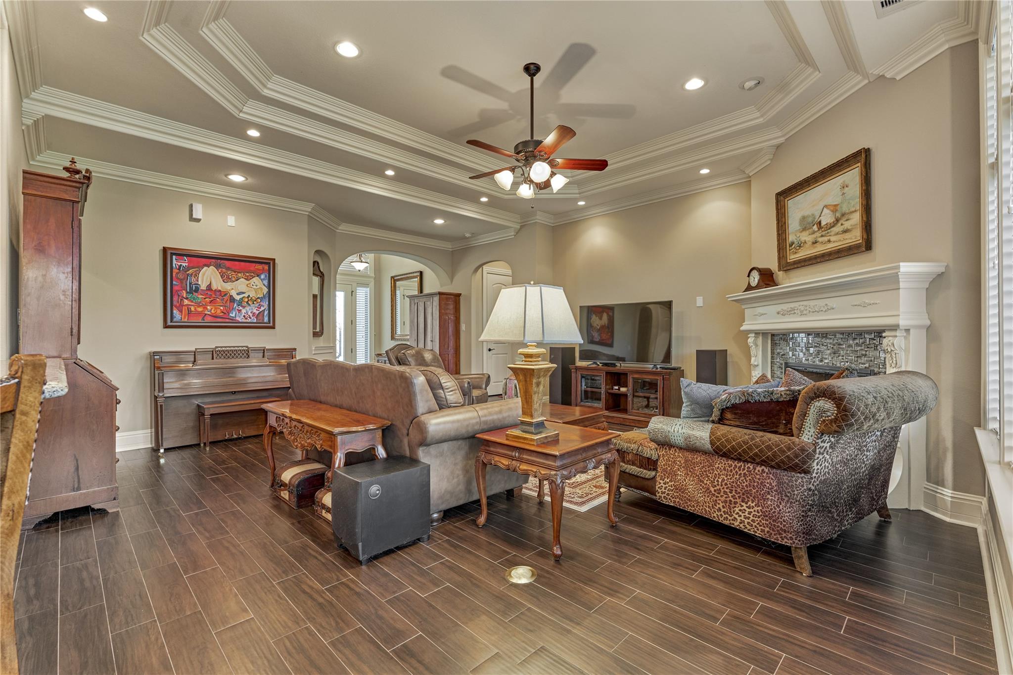 Furnished living room with a white fireplace, piano, and ornate crown molding.