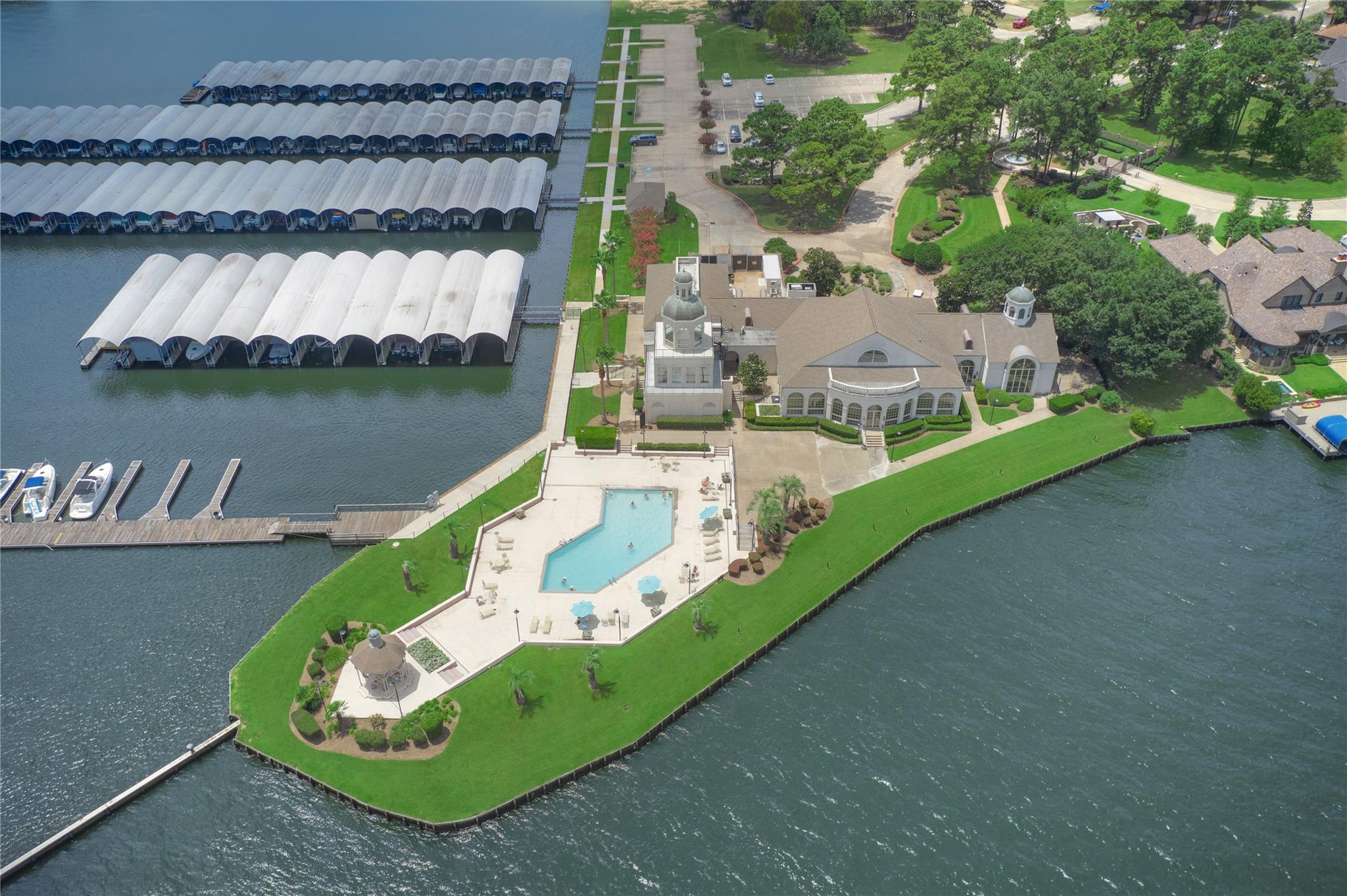 Waterfront clubhouse and pool beside marina slips and open water.