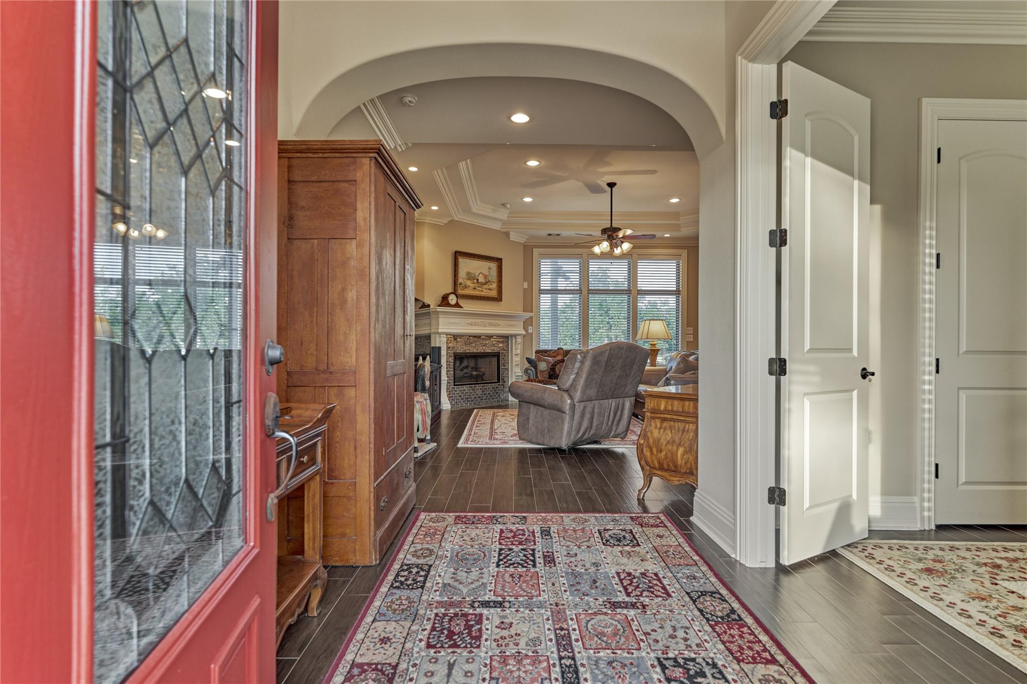Entryway leading to a living room with an arched opening, fireplace, and patterned rugs.