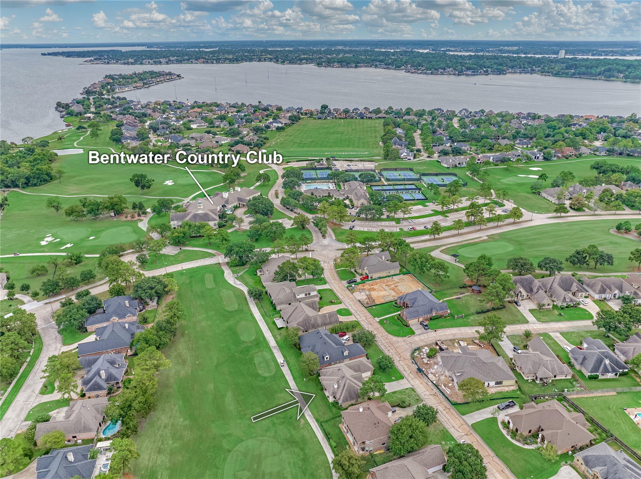 Aerial view of homes beside Bentwater Country Club and Lake Conroe, with an arrow marking the property location.