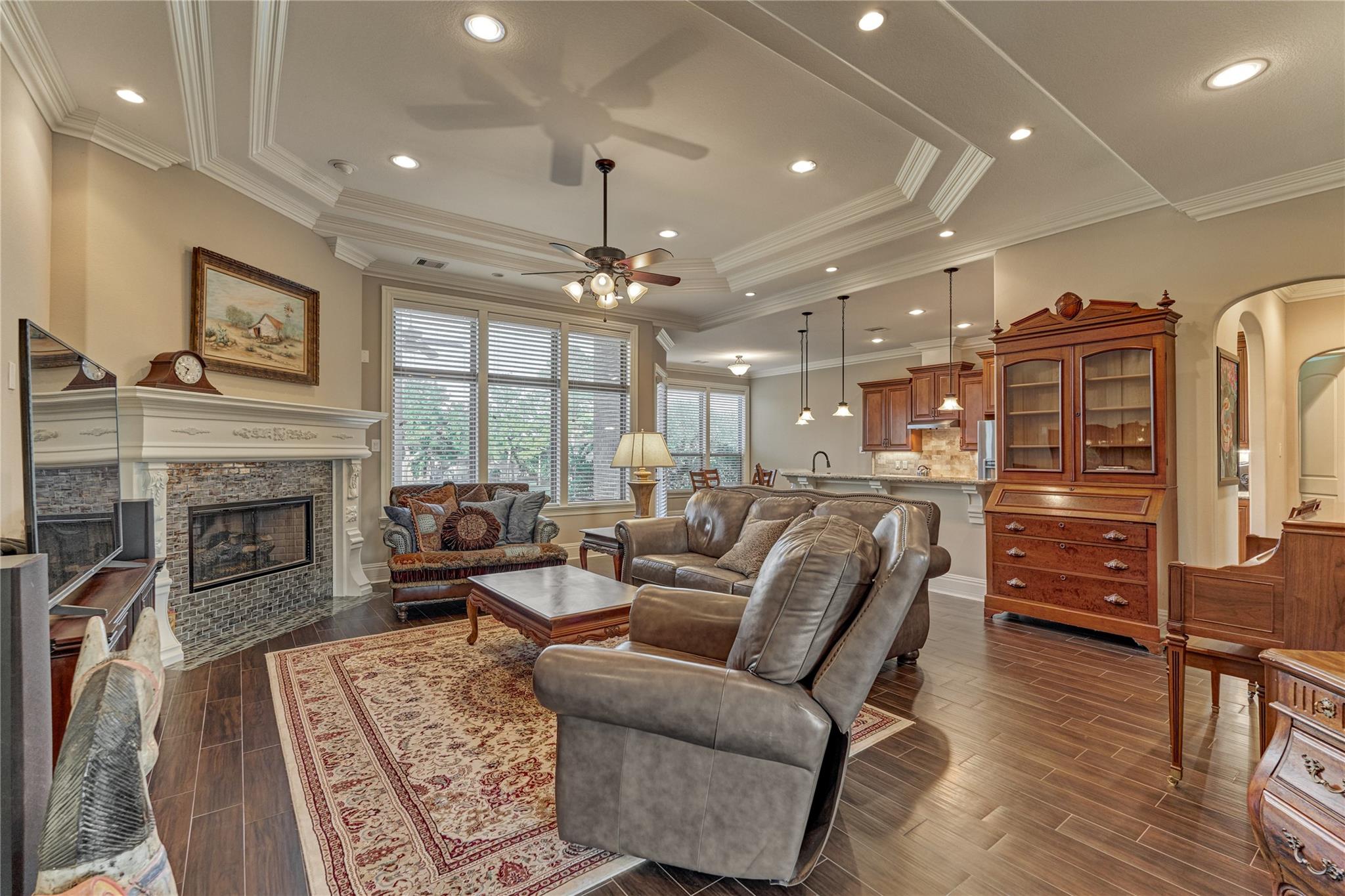 Furnished living room with a stone fireplace, leather seating, shuttered windows, and an open kitchen.