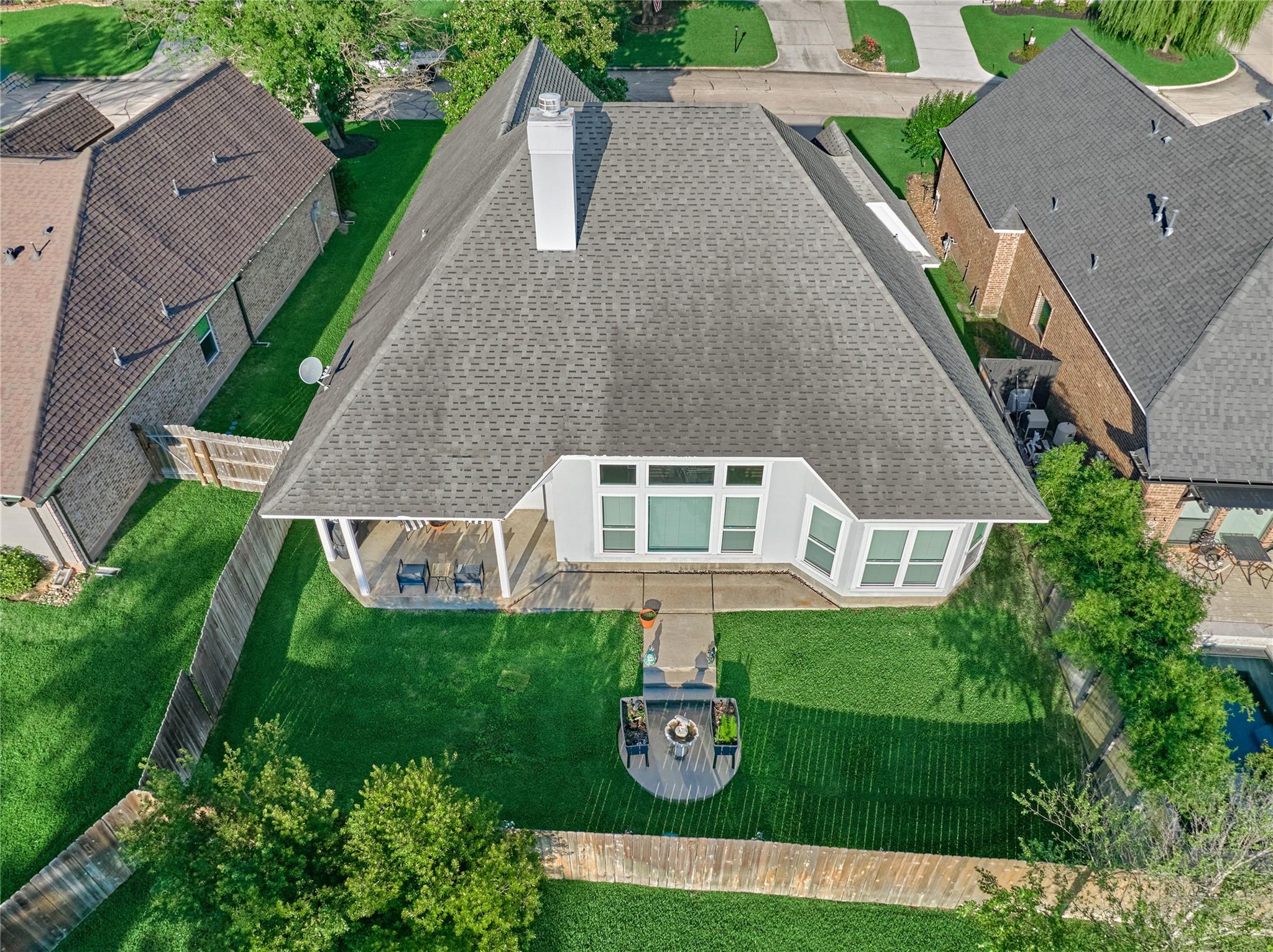 Aerial view of a home with a covered patio and fenced backyard.