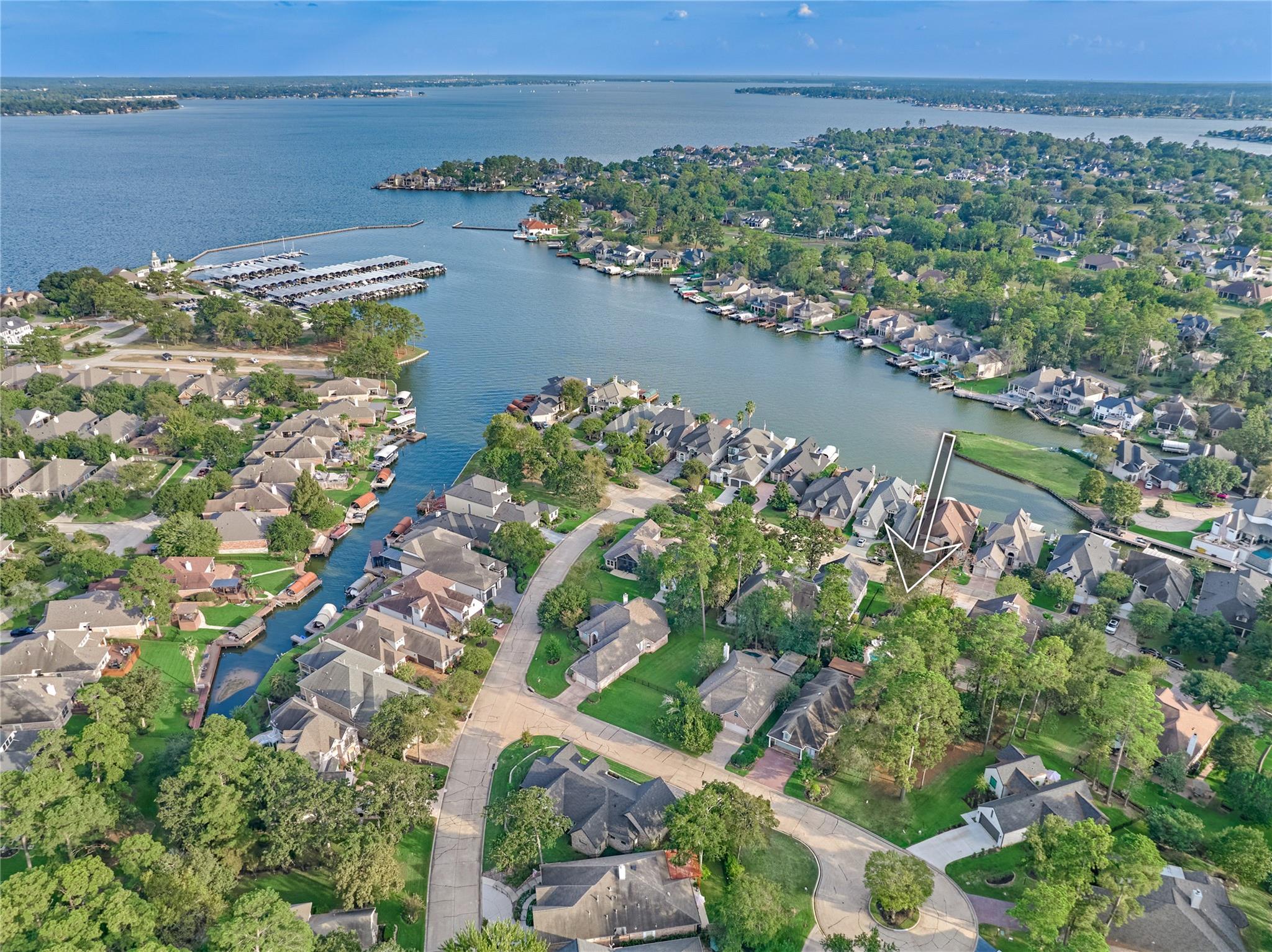 Aerial neighborhood view marking the home beside a canal, with a lake and marina beyond.
