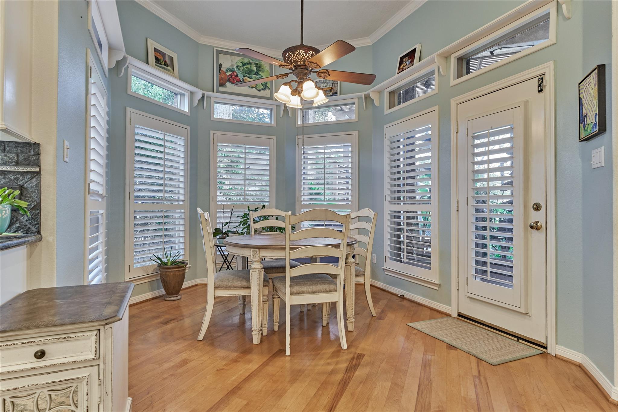 Breakfast nook with a round table, plantation shutters, and a glass-paneled door.