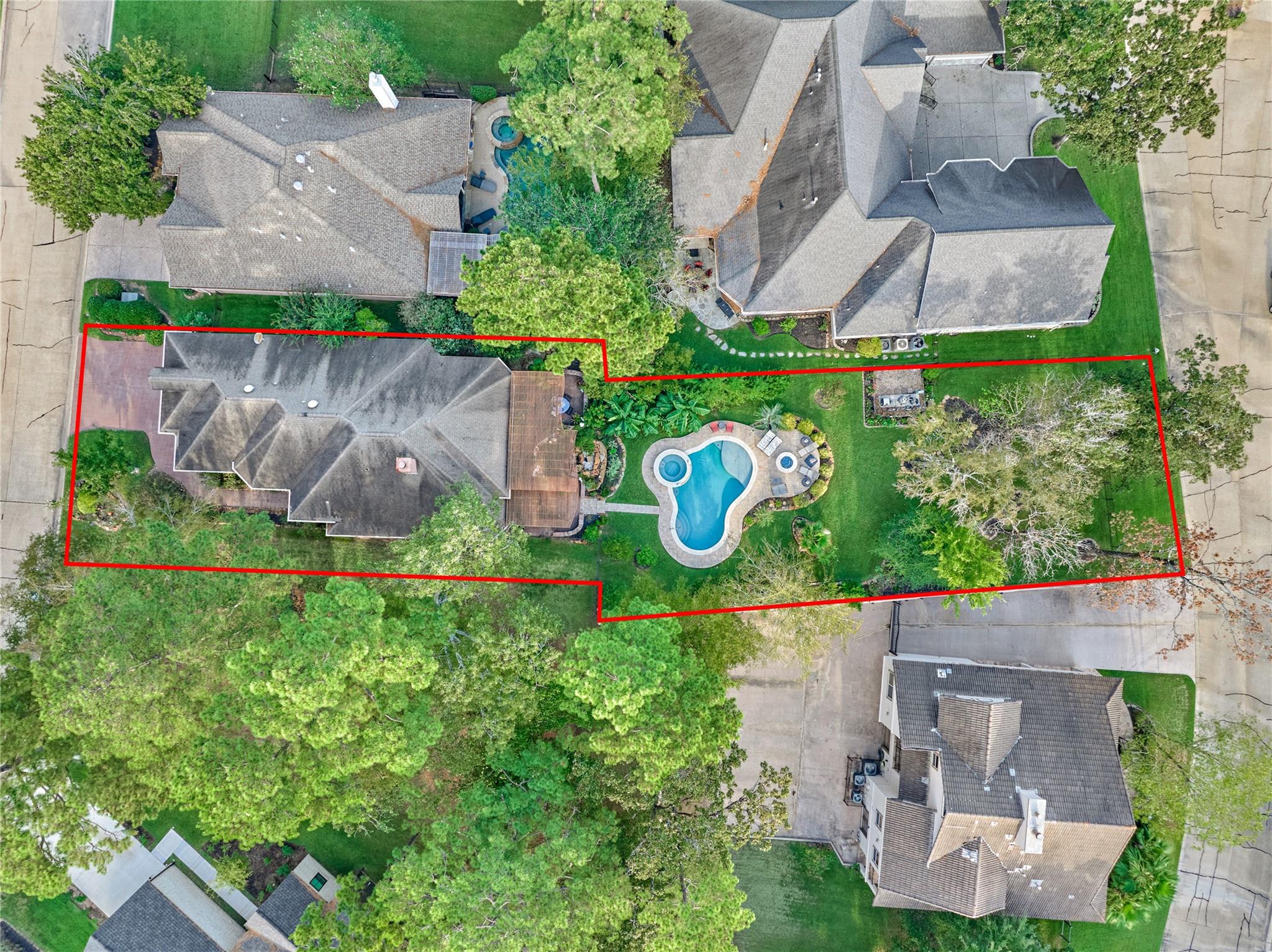 Aerial view of the red-outlined property with a backyard pool, patio, and mature trees.