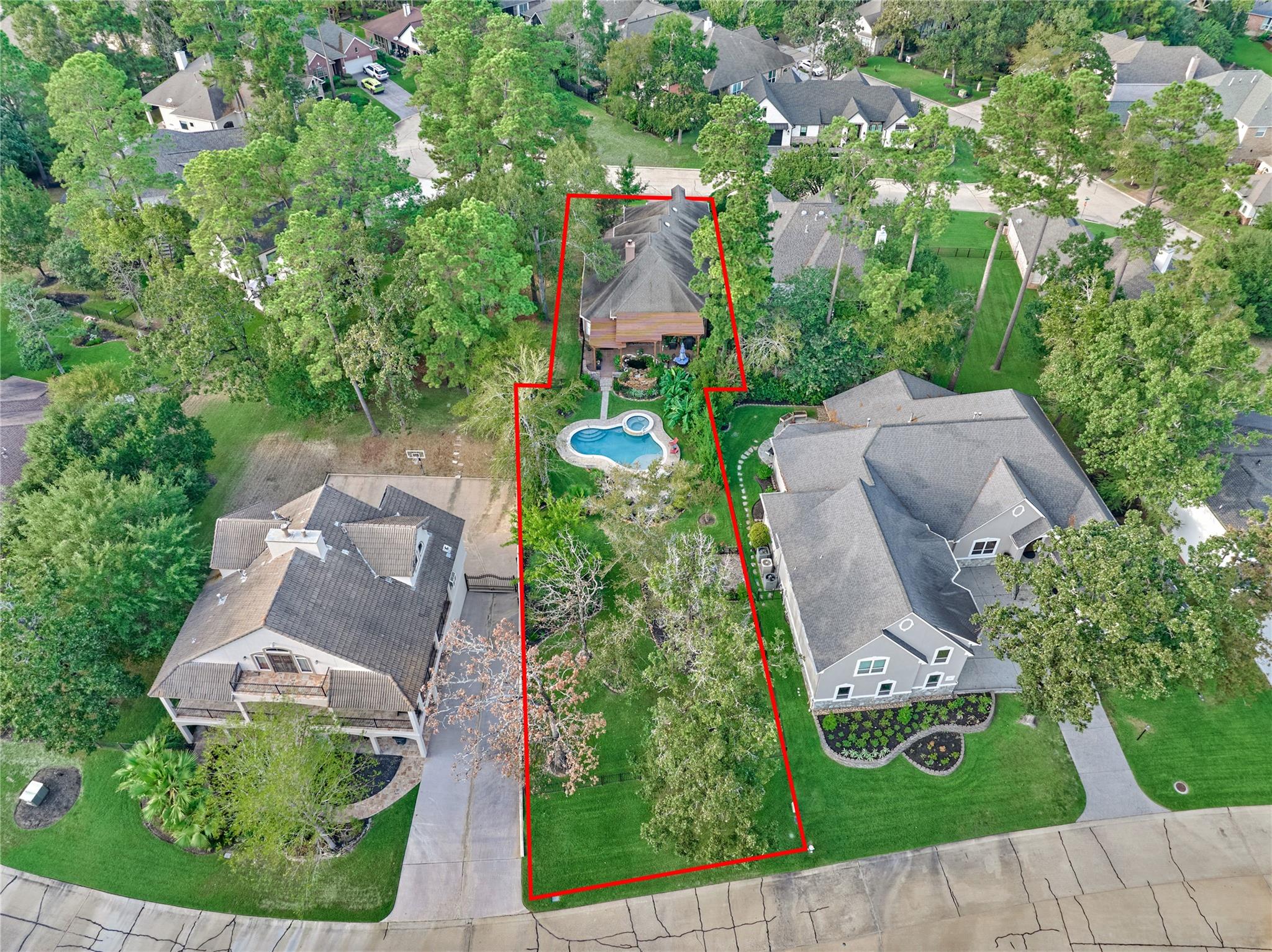 Aerial view of a tree-filled property with a swimming pool, outlined in red.