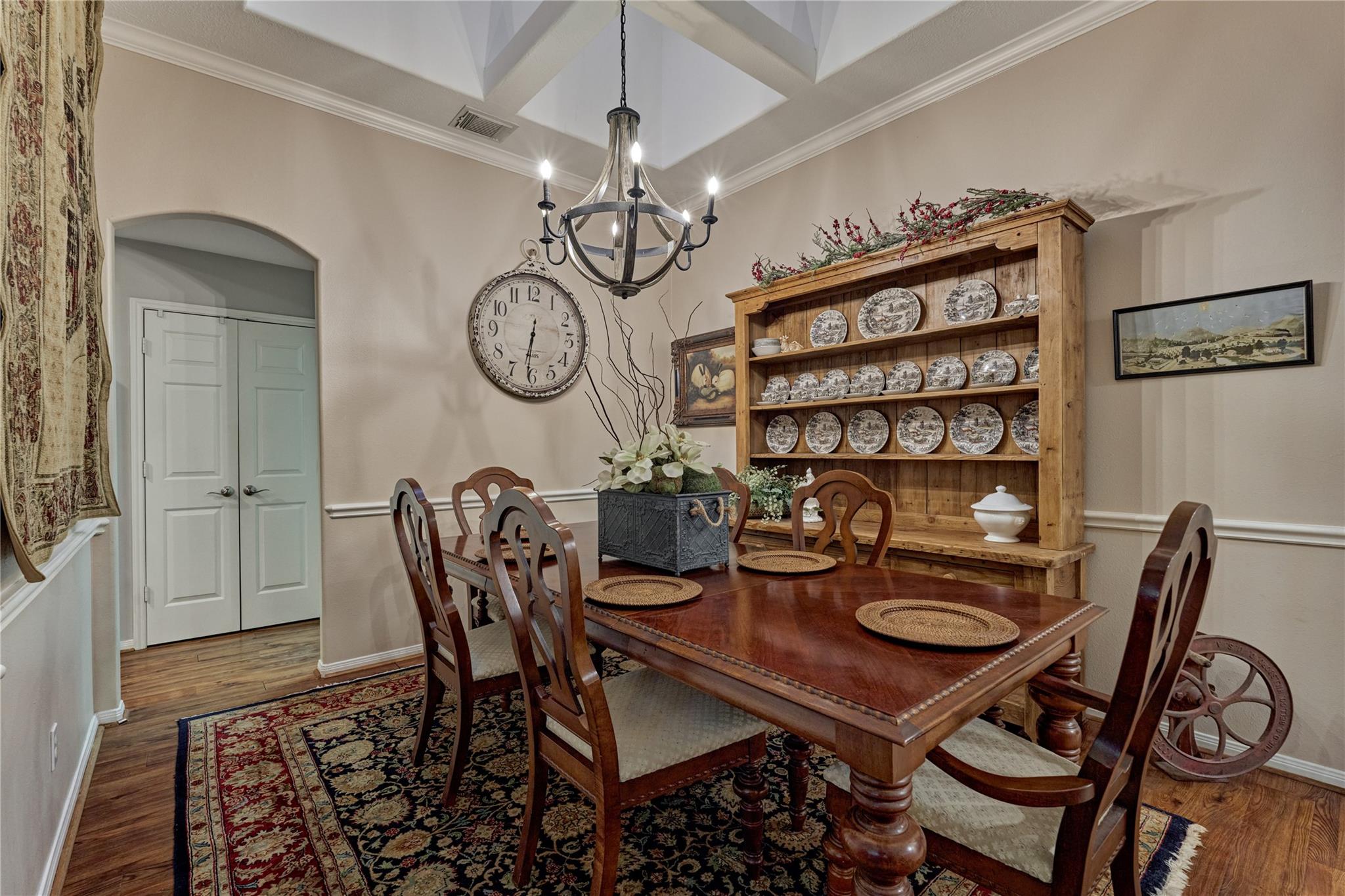 Dining room with a polished wood table, china hutch, patterned rug, and coffered ceiling.