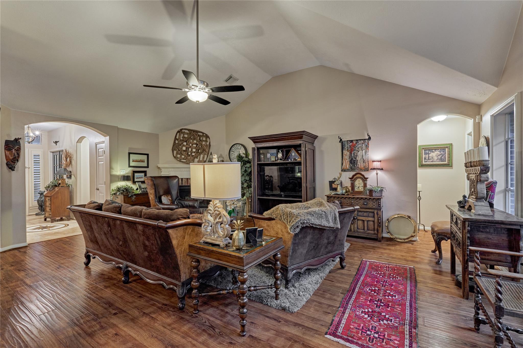 Living room with vaulted ceiling, traditional seating, and warm wood floors.