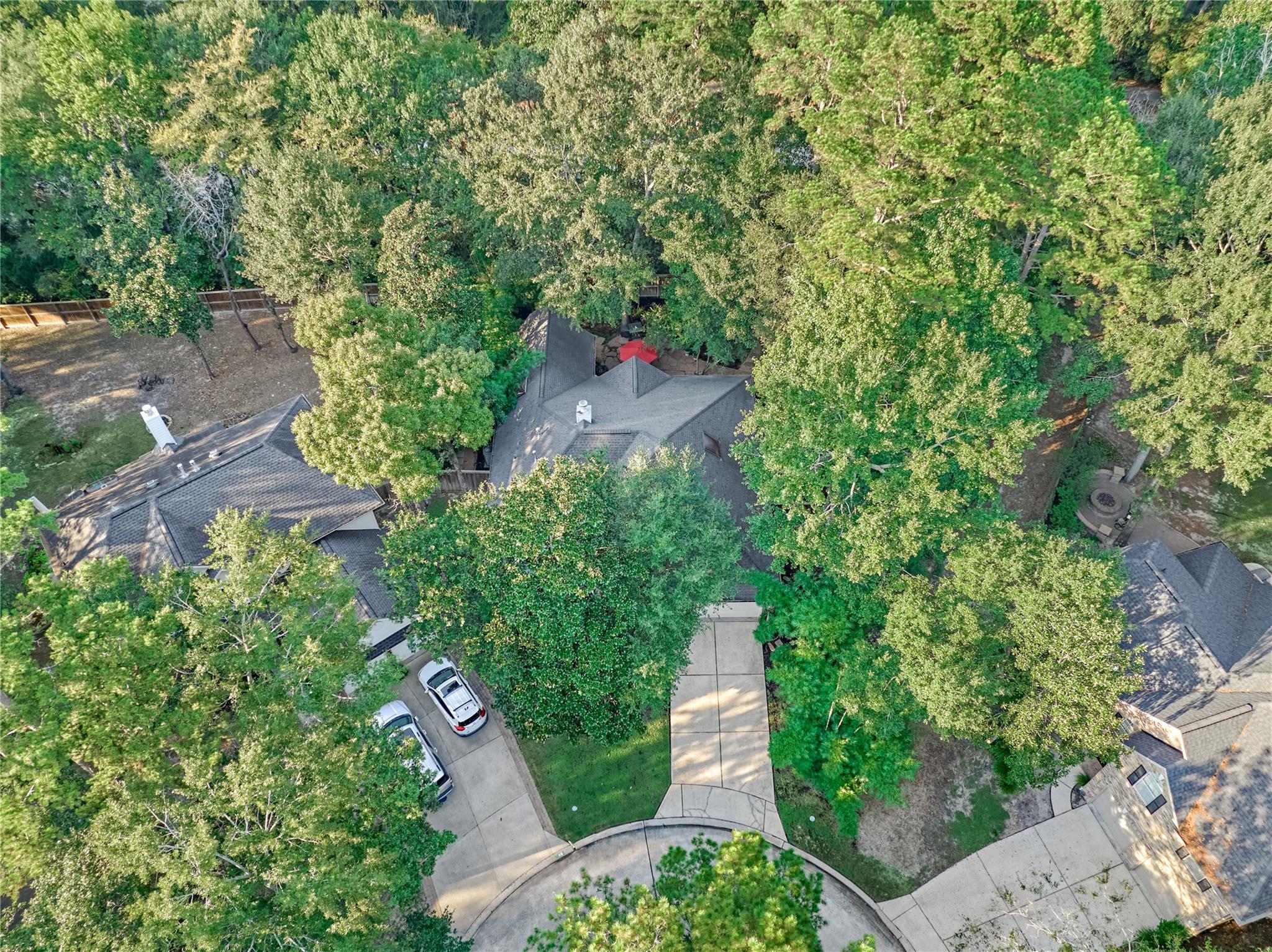 Aerial view of a tree-shaded home, its driveway, and the surrounding cul-de-sac.