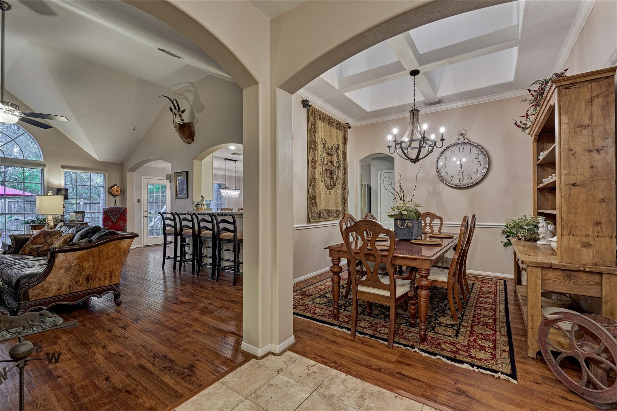 Open-plan living and dining area with wood floors, a vaulted ceiling, and a chandelier over the dining table.