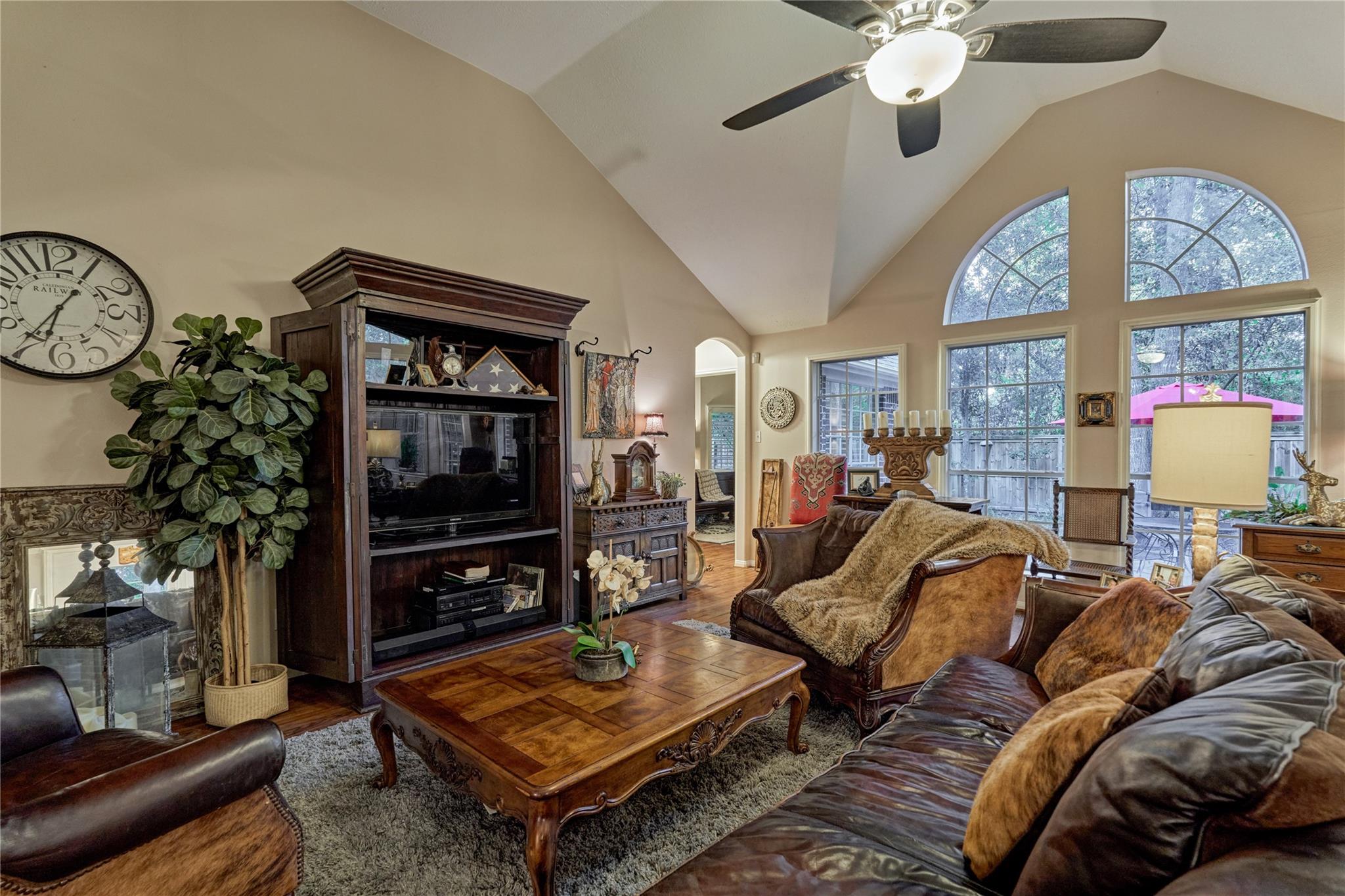 Living room with vaulted ceiling, arched windows, leather sofas, and ornate wooden furnishings.