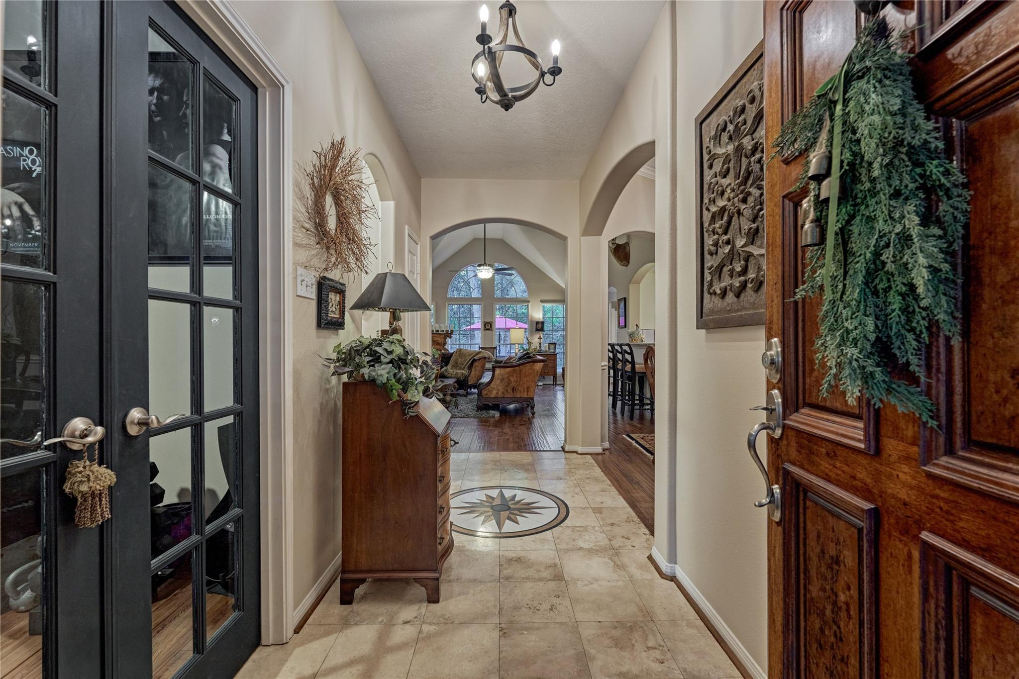 Entry hall with a compass rose floor medallion, carved wooden front door, and arched view into the living room.