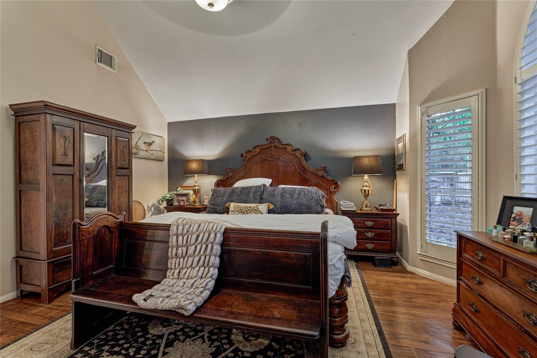 Furnished bedroom with a carved wooden bed, matching furniture, and plantation shutters.