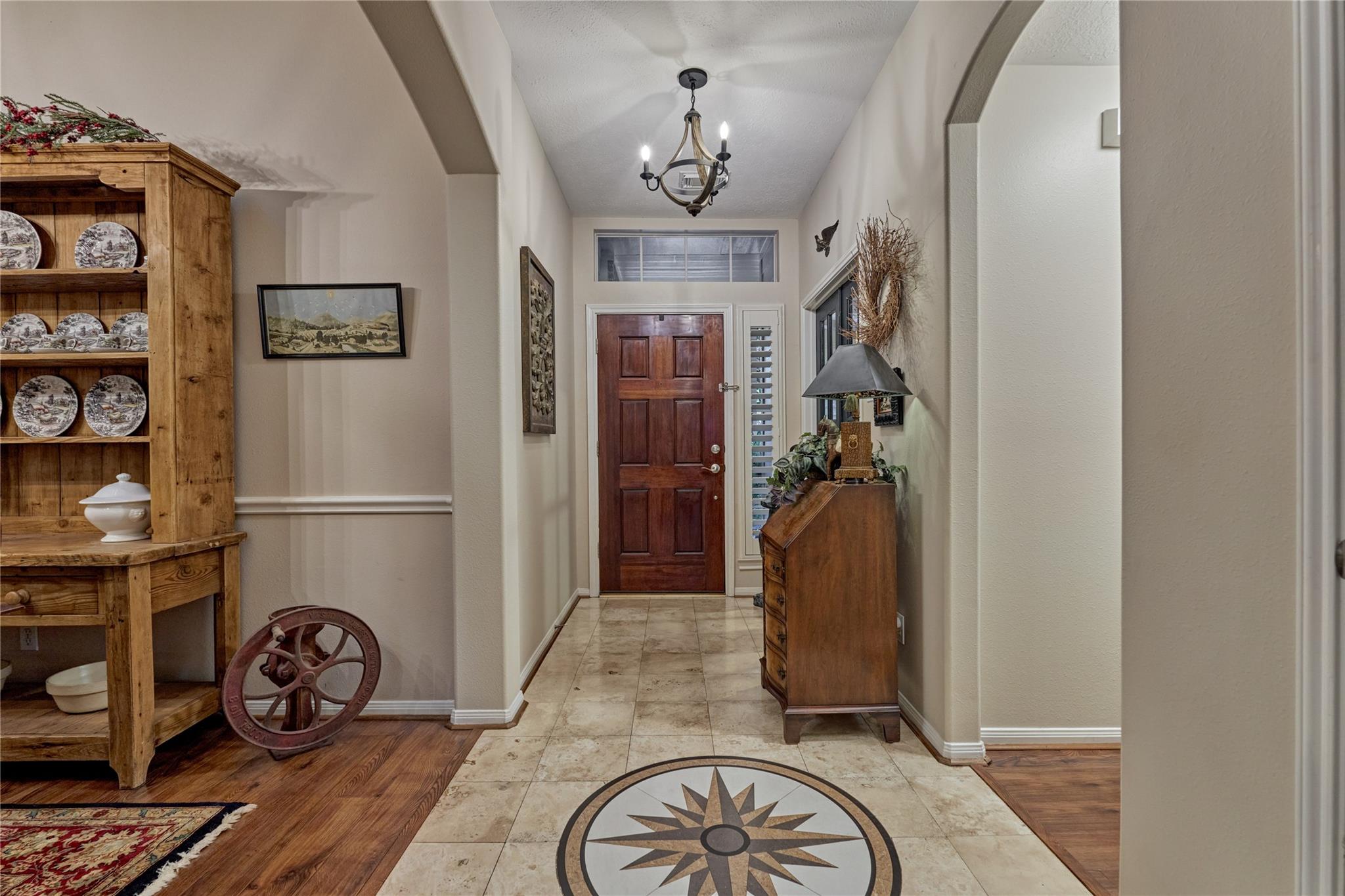 Entry hall with a compass rose tile medallion, wooden hutch, and dark wood front door.