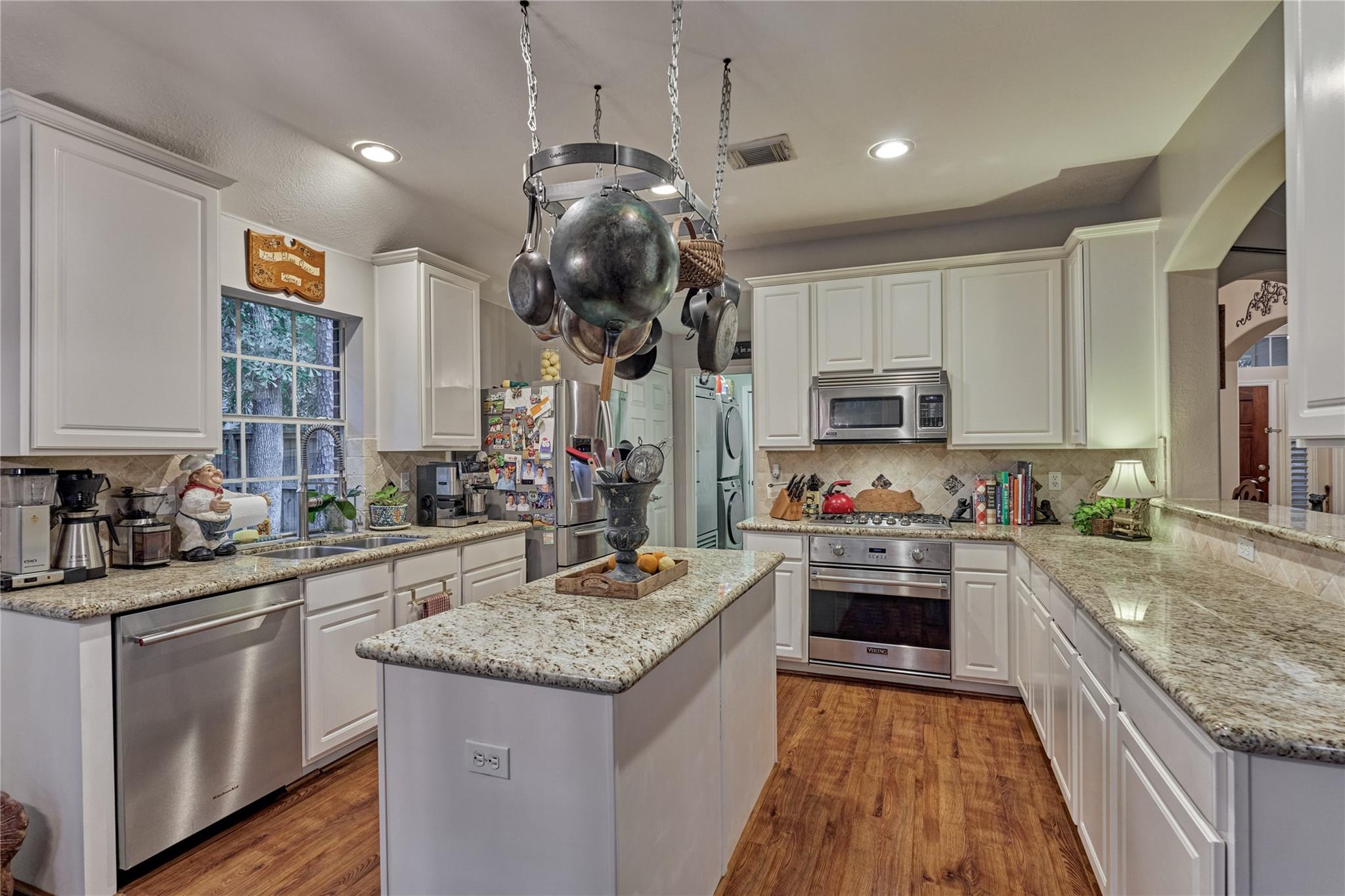 Kitchen with white cabinetry, granite counters, a central island, and stainless steel appliances.