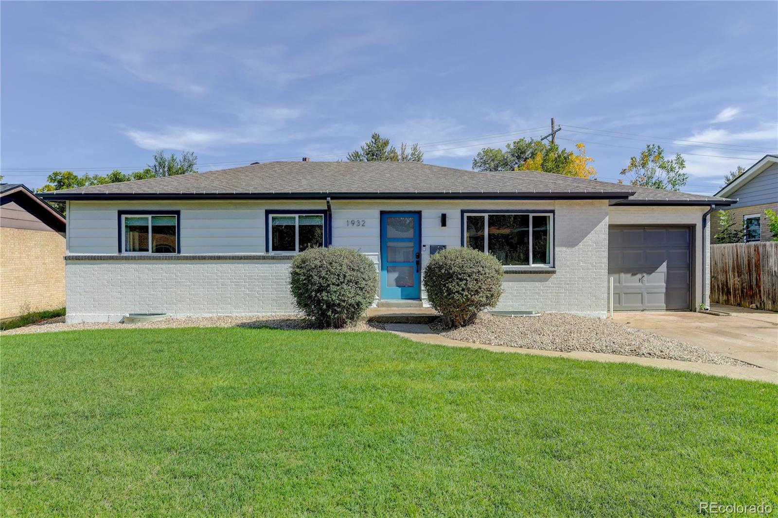 Single-story home with a blue front door, gray brick facade, attached garage, and broad lawn.
