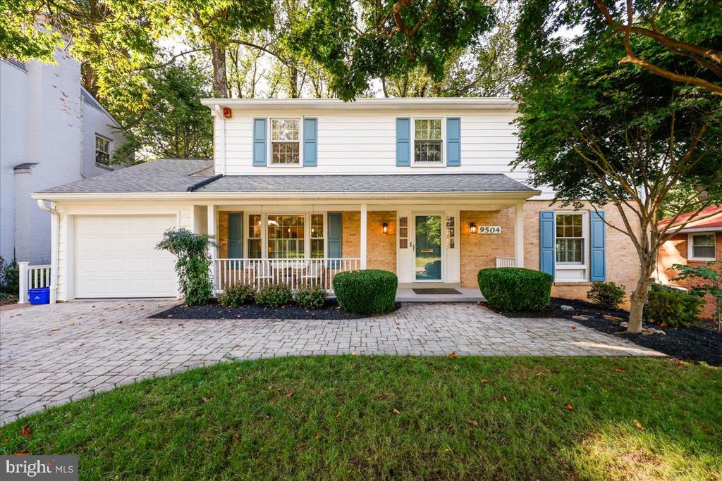 Two-story white house with blue shutters, a brick entry, and a covered front porch.
