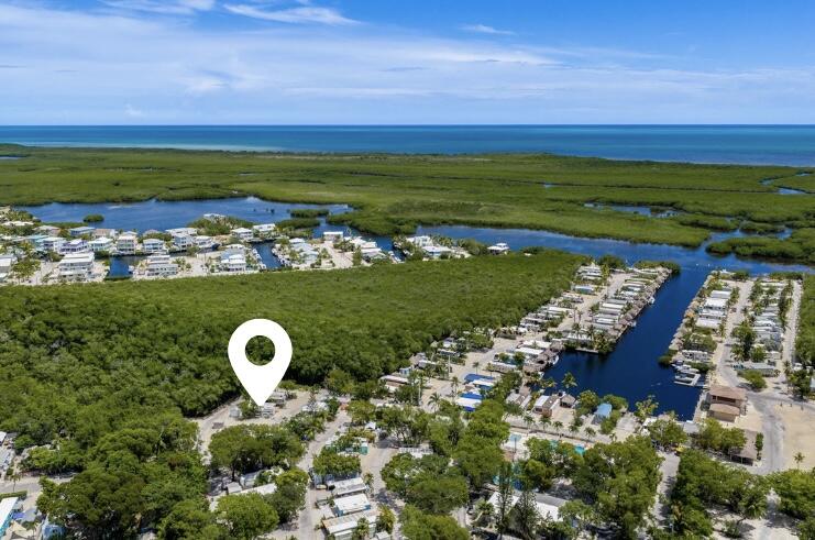 Aerial view of a coastal community beside a canal, with marshland and ocean beyond.