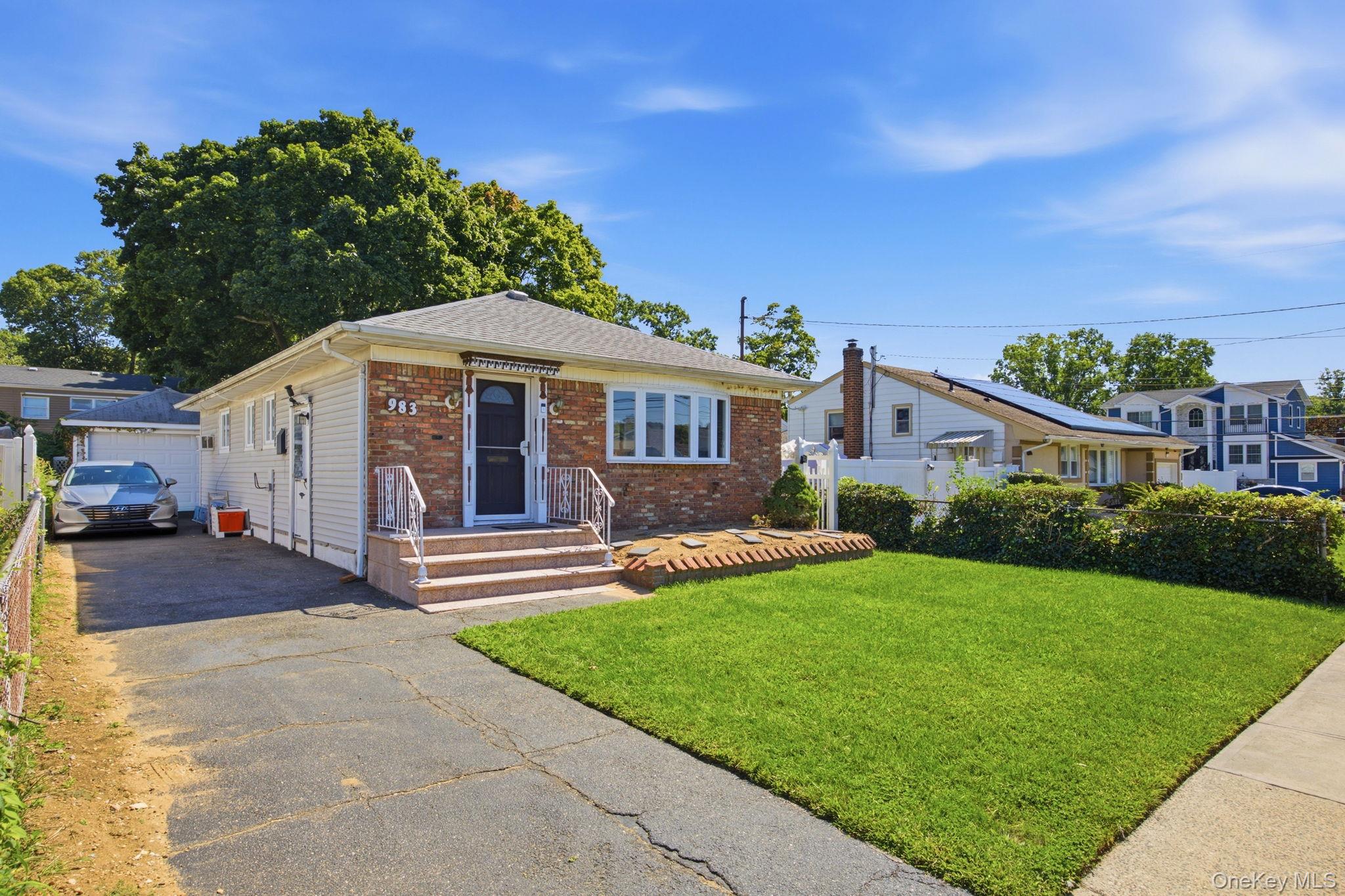 Single-story brick-front house with a driveway, front steps, and a broad green lawn.