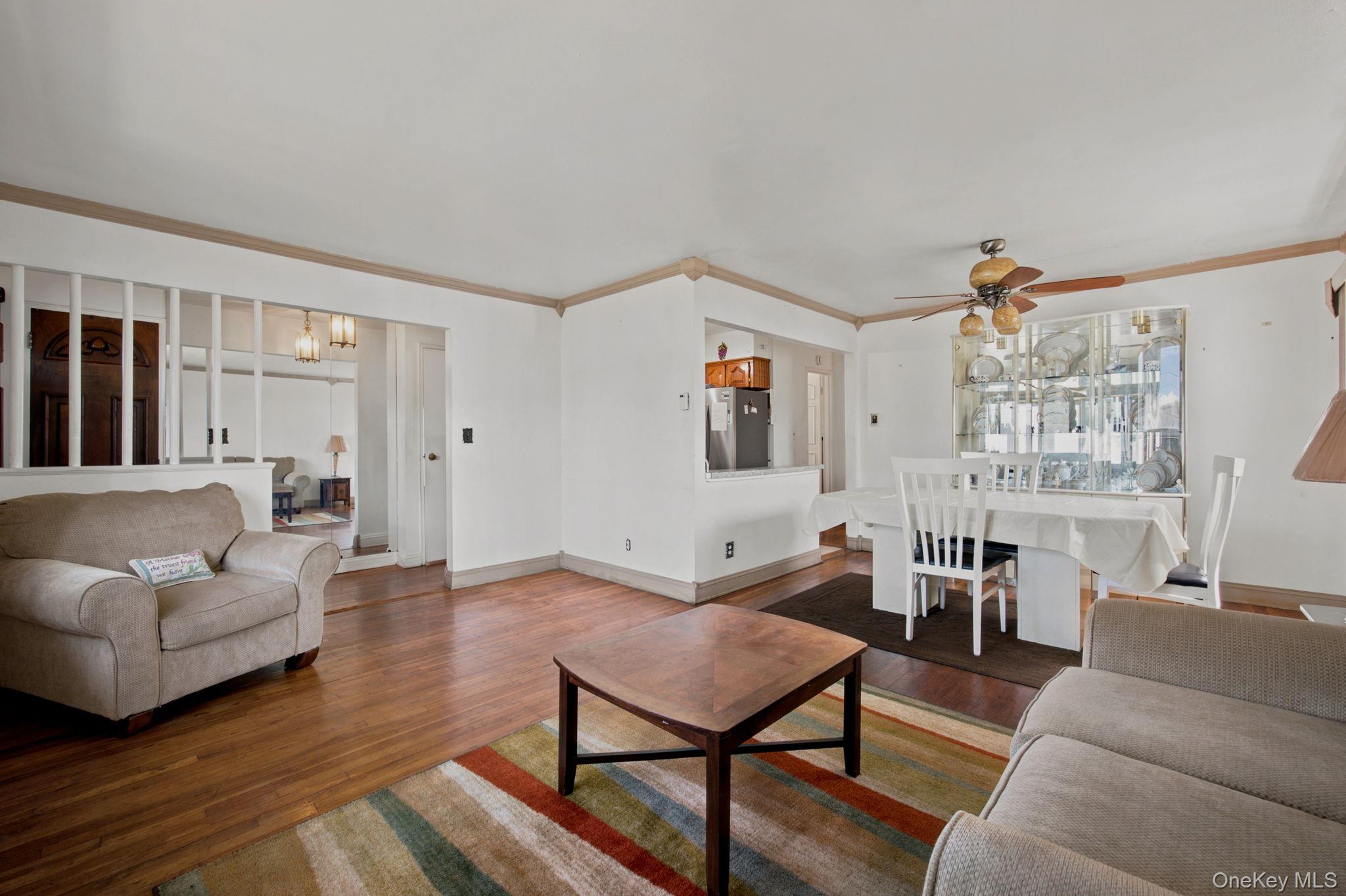 Furnished living and dining room with hardwood floors, striped rug, and glass-front display cabinet.
