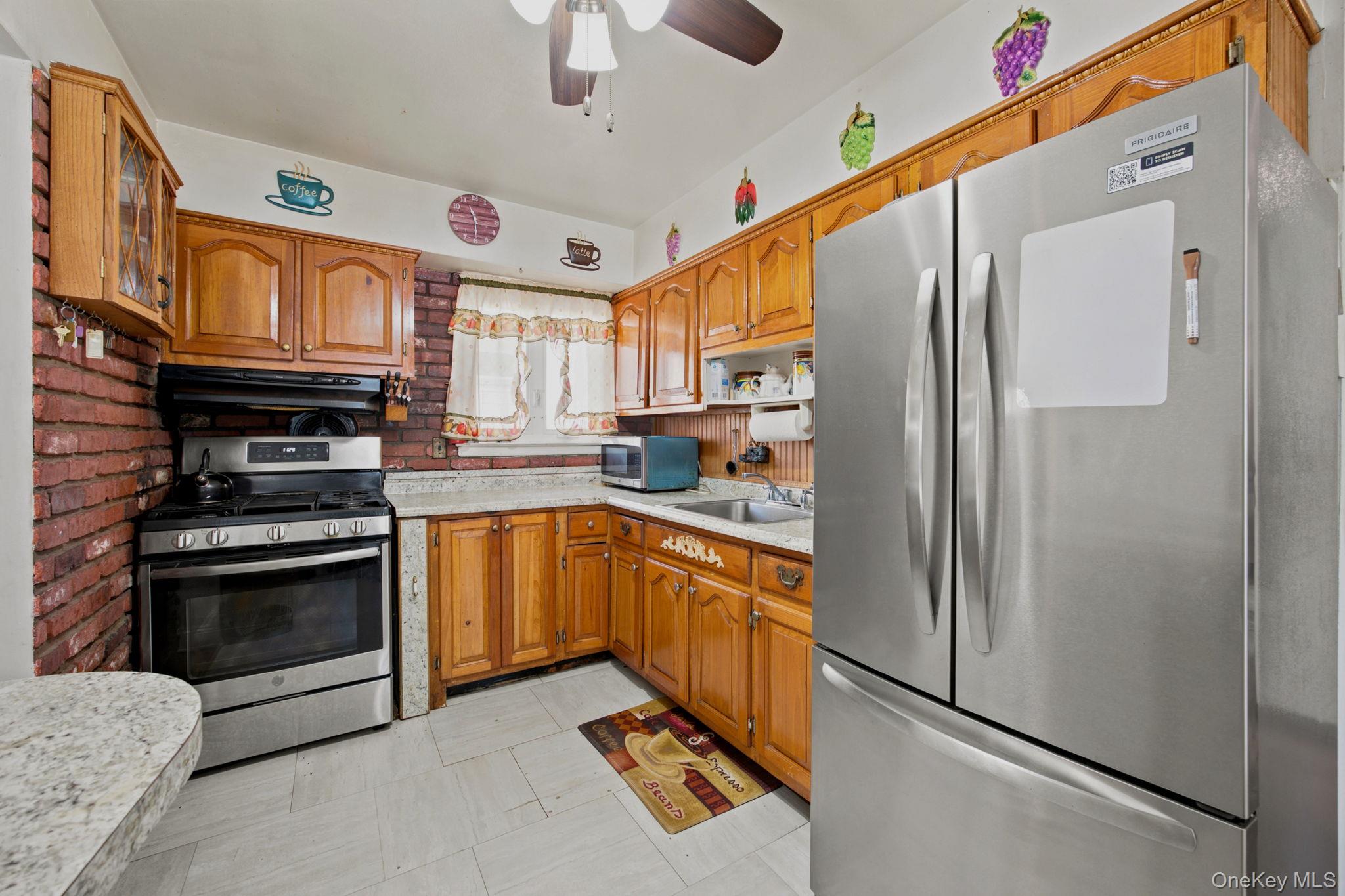 Kitchen with wood cabinets, brick backsplash, gas range, and a large stainless steel refrigerator.