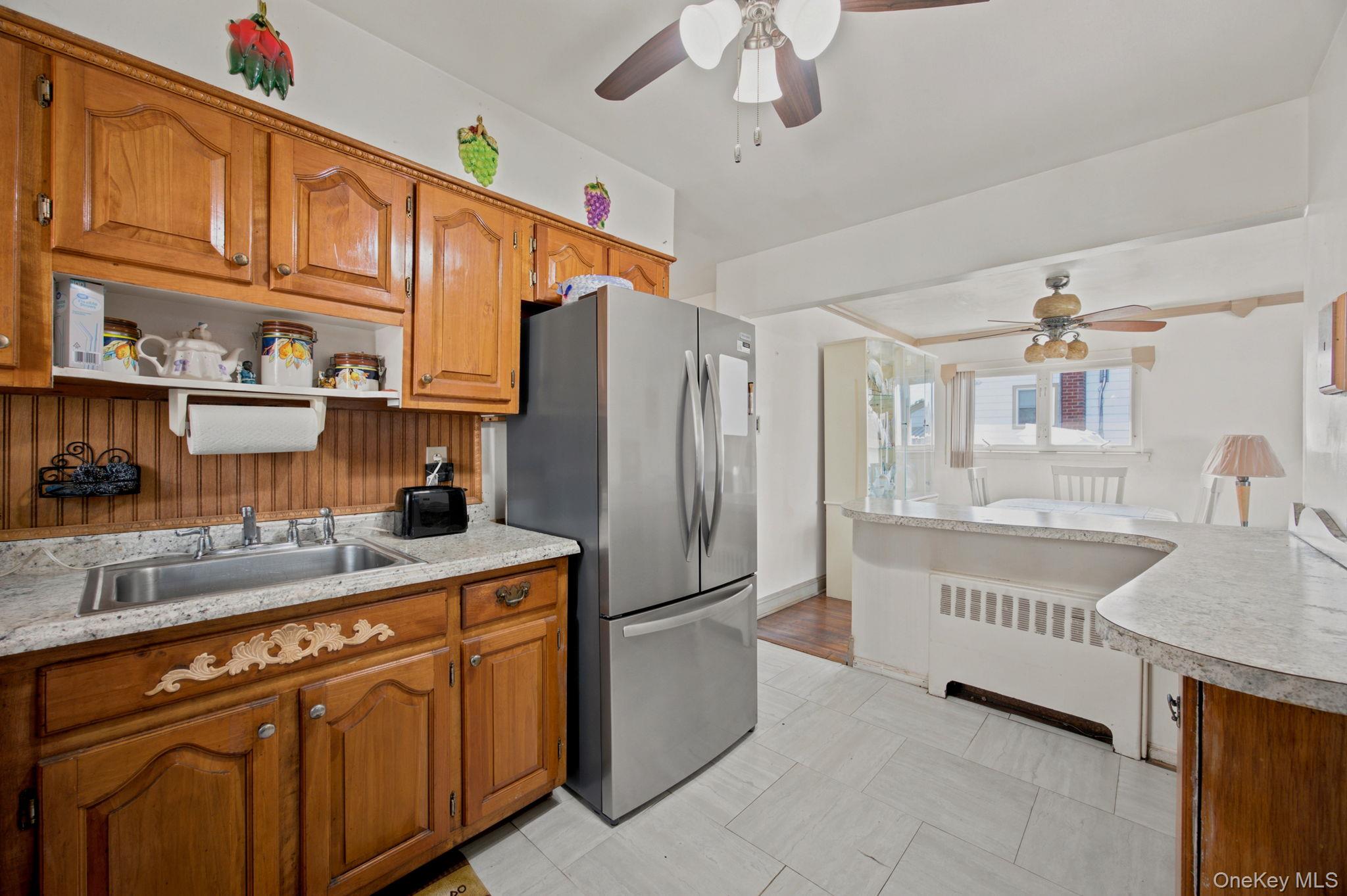 Kitchen with ornate wooden cabinets, granite counters, stainless steel refrigerator, and adjoining dining area.
