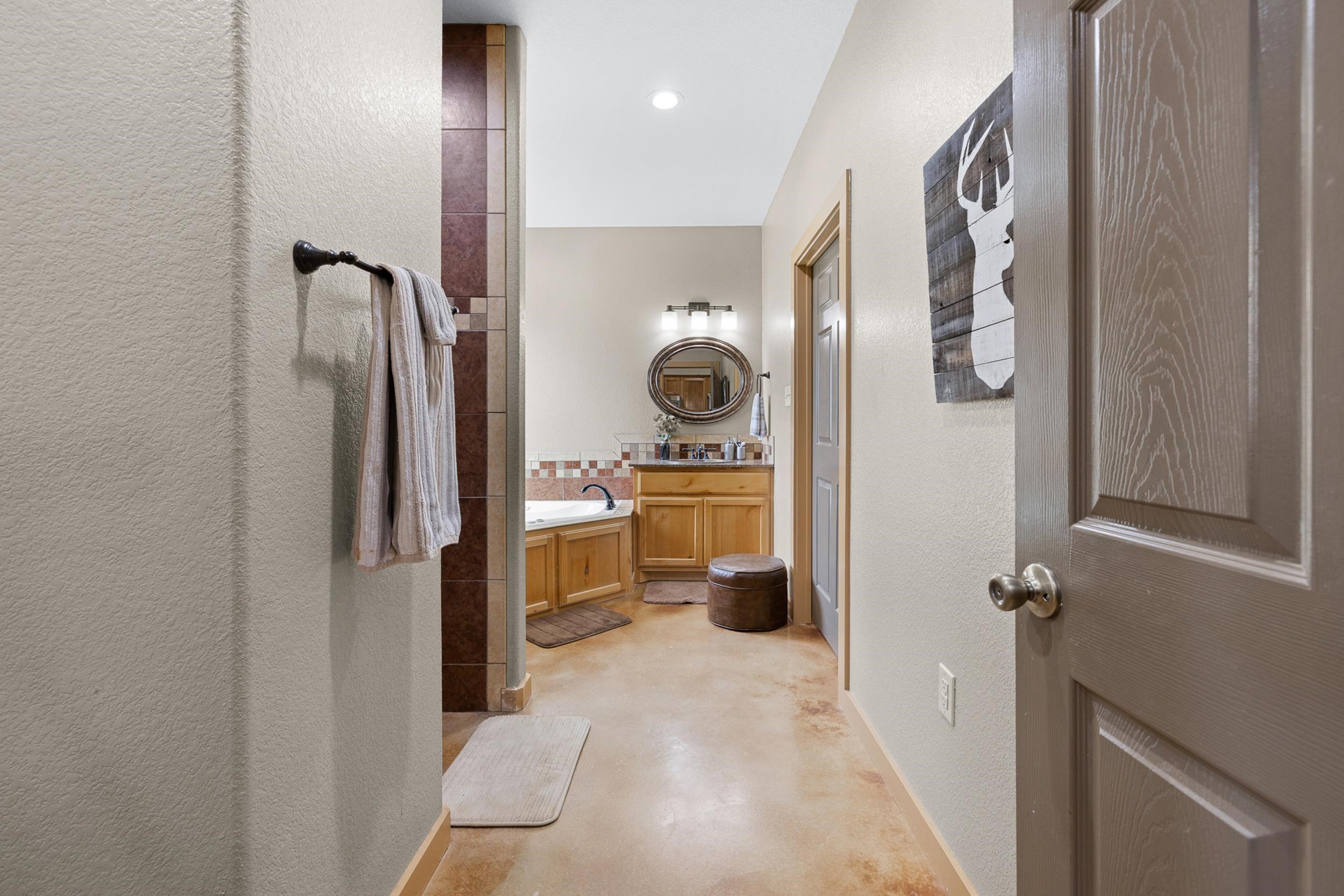 Bathroom with a soaking tub, wood vanity, oval mirror, and tiled accents.