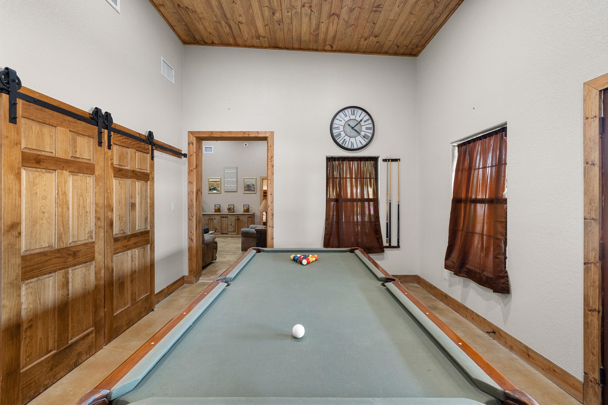 Game room with a pool table, rustic sliding barn doors, and a wood-plank ceiling.