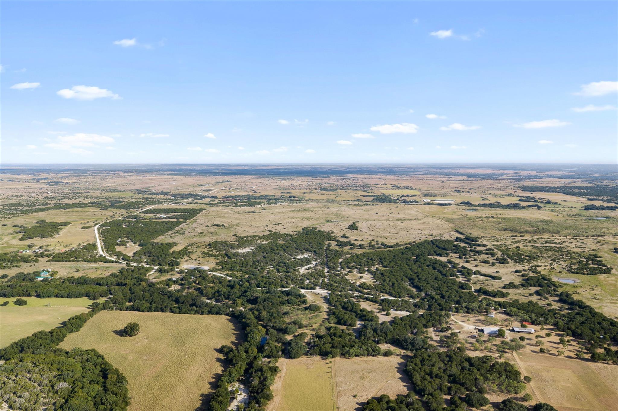 Aerial view of rural land with open fields, scattered trees, and winding country roads.