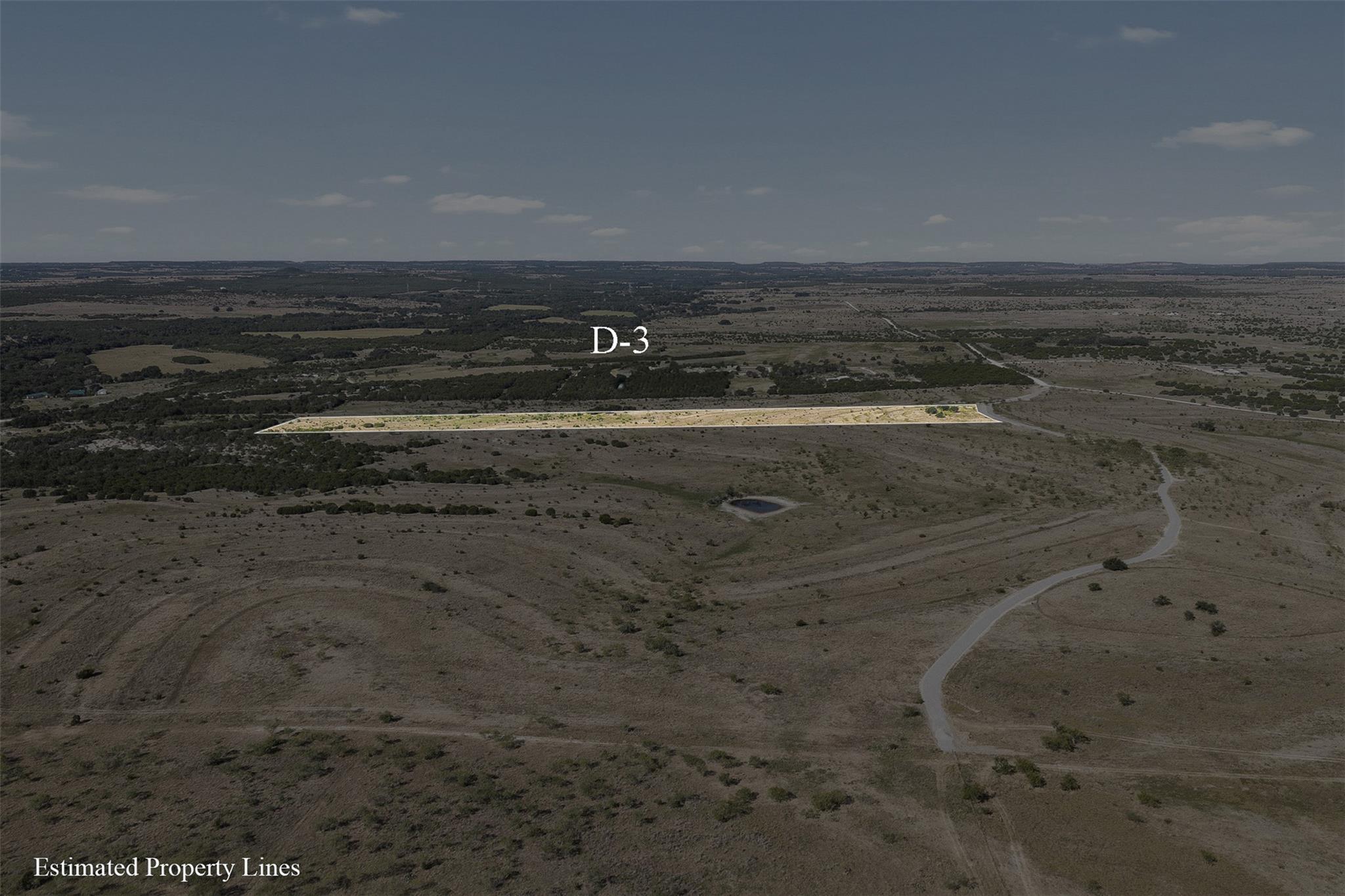 Aerial view of the long, narrow D-3 land parcel outlined across rural terrain beside a winding road.