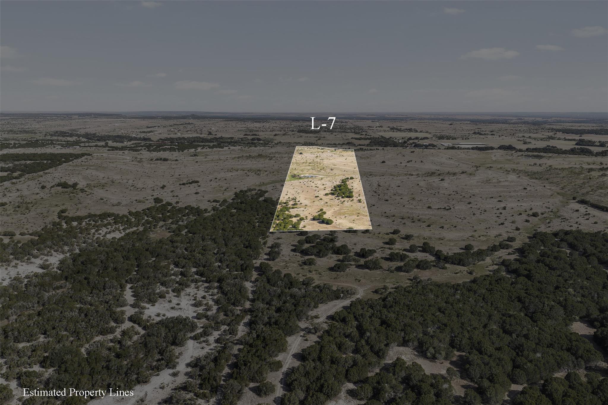 Aerial view of L-7, a scrubland parcel outlined among scattered trees near a winding dirt road.