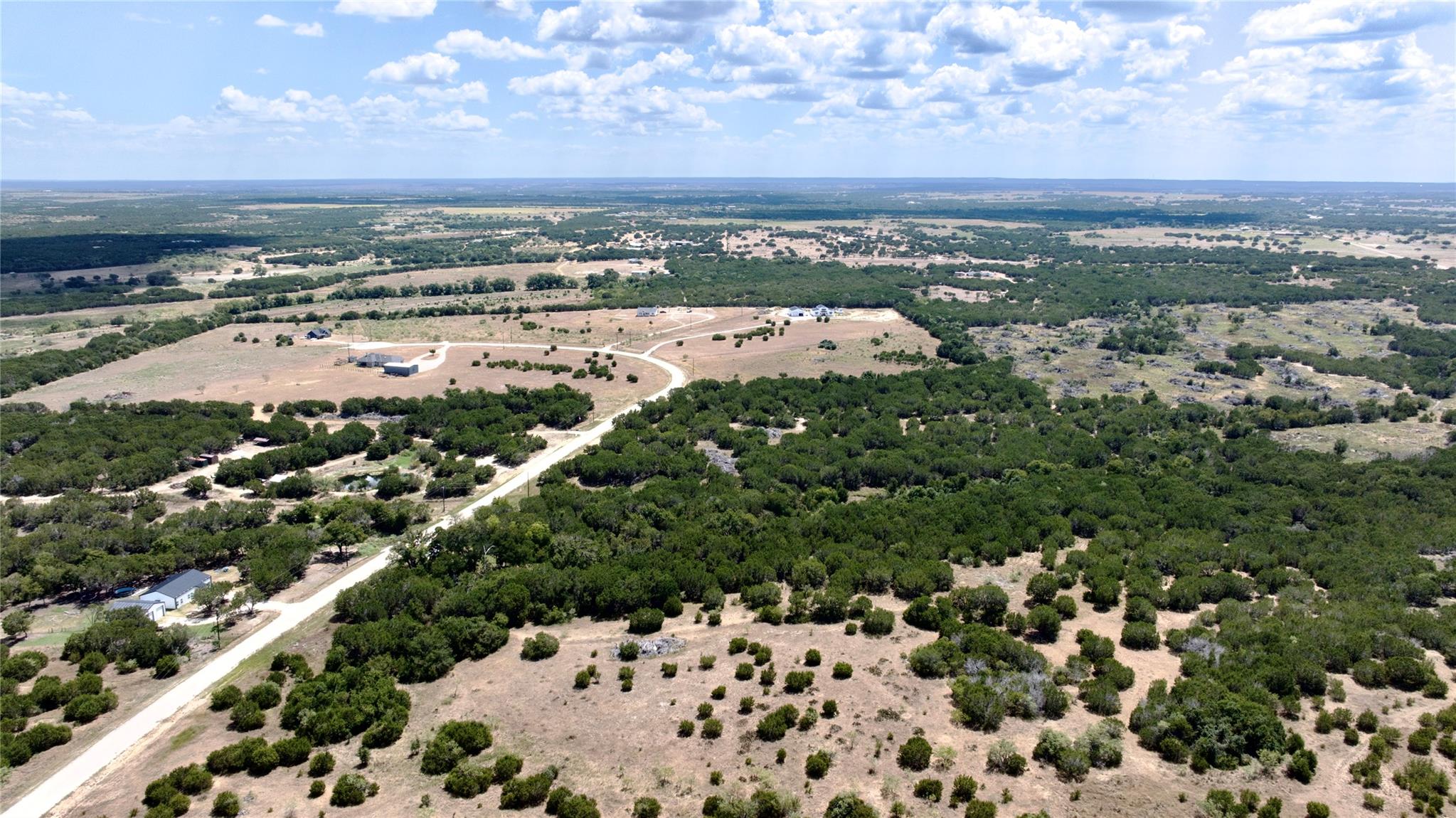 Aerial view of scrub-covered land, a winding road, and scattered homes near Lampasas.