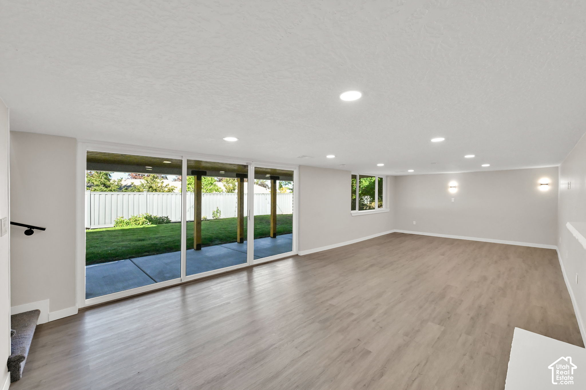 Vacant living room with wide sliding glass doors overlooking a covered patio and fenced backyard.