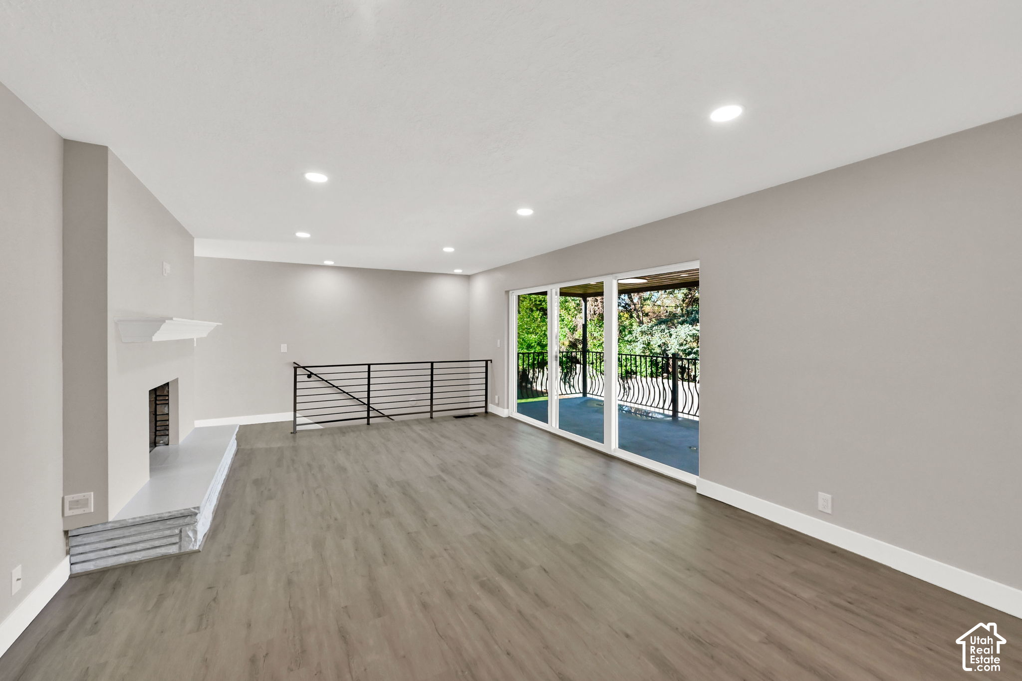 Vacant living room with a fireplace, gray flooring, and sliding glass doors to a balcony.